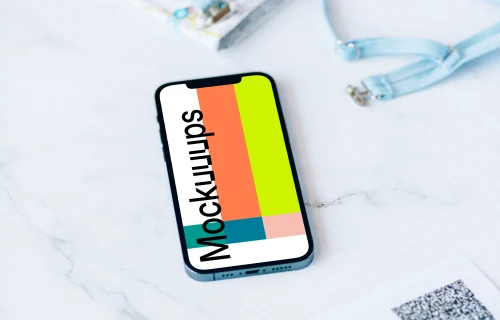 iPhone 12 Pro mockup on a white table beside a bikini