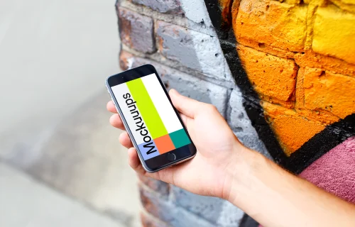 iPhone 6s Space Gray mockup next to the graffiti wall