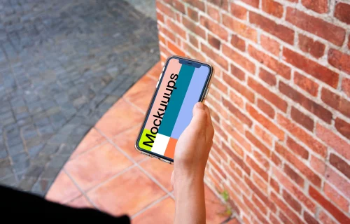 iPhone mockup held beside a brick wall