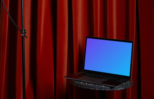 MacBook mockup on a black stool with a tall lamp hanging above it