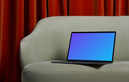 MacBook mockup on a couch with a red curtain in the background