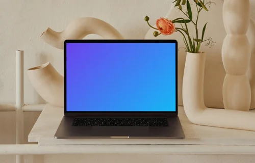 MacBook mockup on a peach colored table with a fancy flower vase