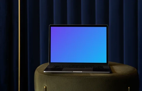 MacBook mockup on a sofa stool with blue curtain in the background