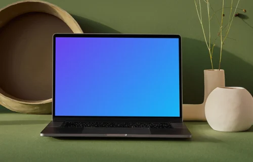 MacBook mockup on a table with flower vase in a green background