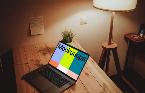 MacBook night mockup on a wooden table with a lamp by the side