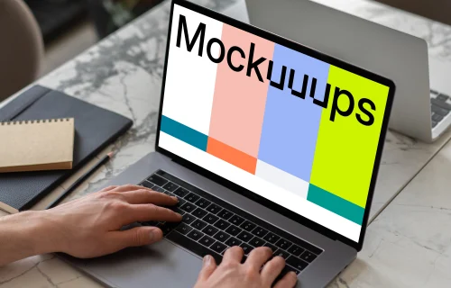 MacBook Pro mockup on a white table beside a notebook