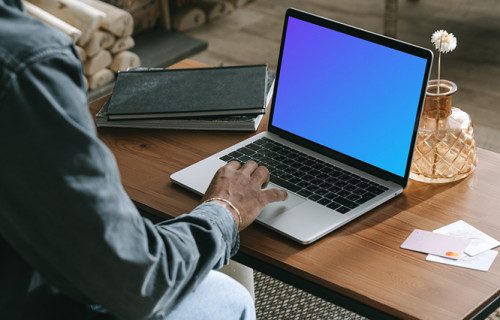 MacBook user shopping with a MacBook on the table and a debit card beside it mockup.