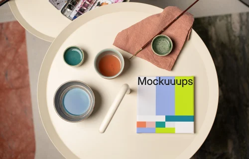 Mockup of a square poster with art supplies on a round table