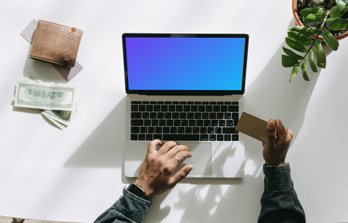 Mockup of User shopping on a Grey MacBook beside some cash and a wallet