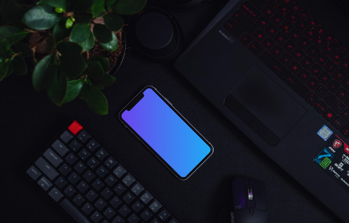 Night iPhone mockup on a table alongside a keyboard and flower pot