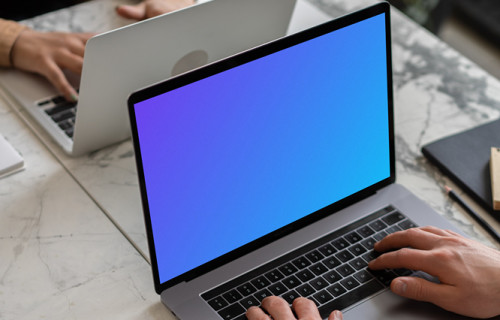 Notebook mockup on a table opposite another MacBook Pro