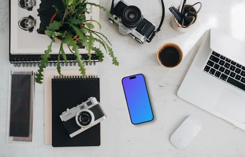 Top view of phone mockup with a MacBook Pro and camera on the side
