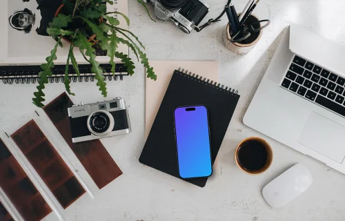 Top view of phone mockup with analog cameras and book