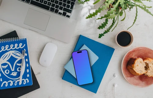 Top view of smartphone mockup next to MacBook and Magic Mouse