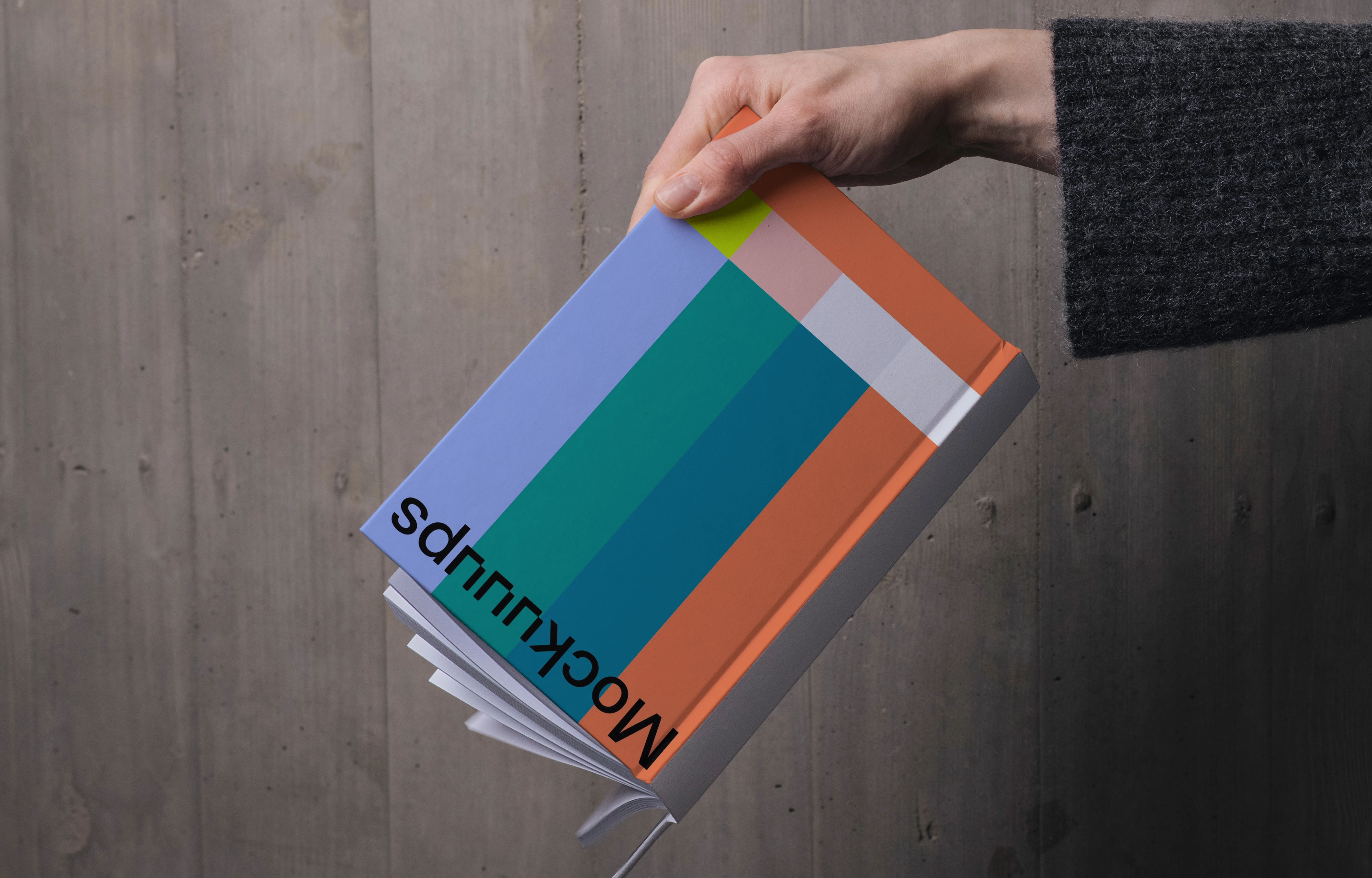 C-format book mockup held against wooden wall
