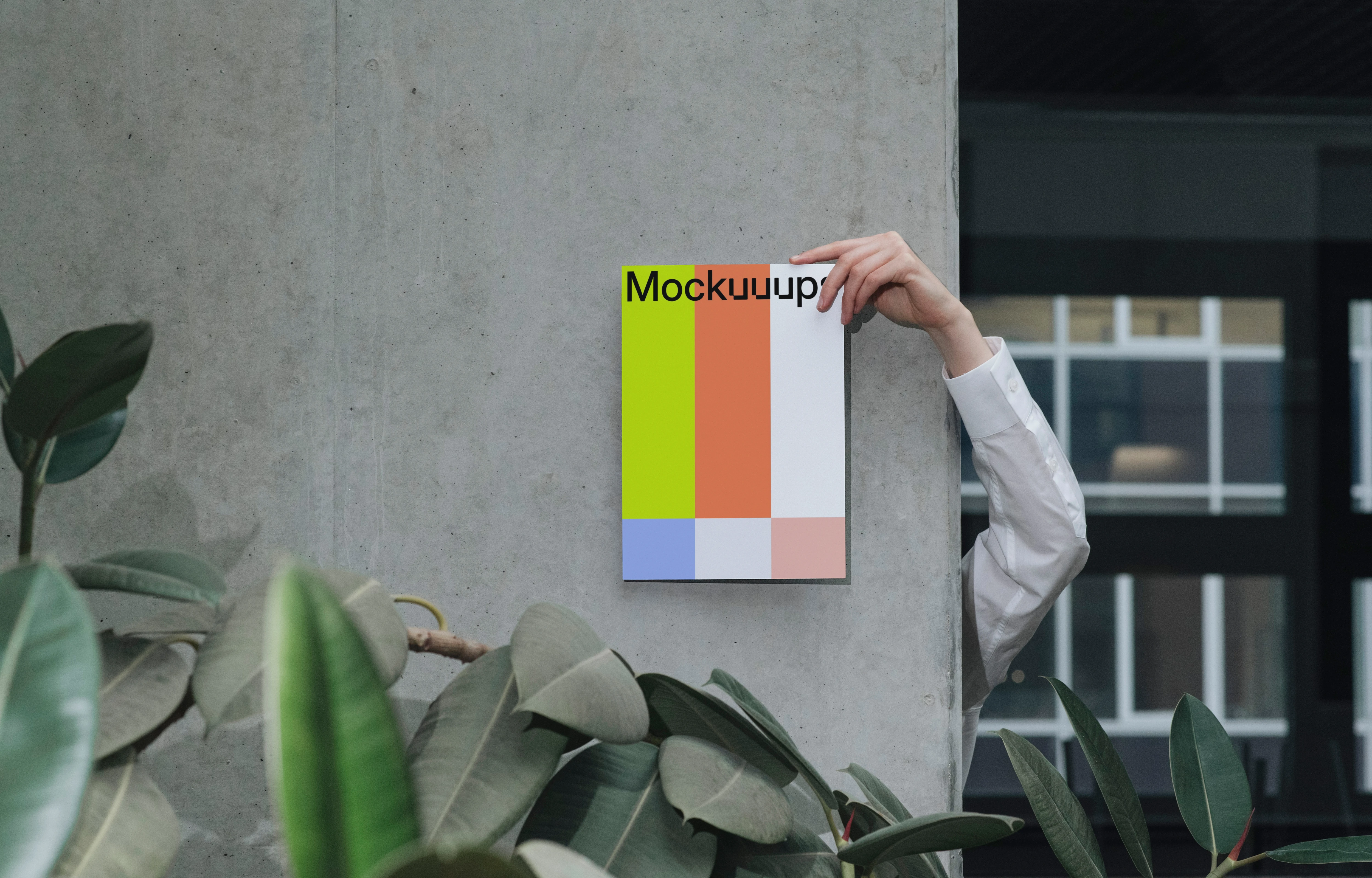 A4 mockup held against a concrete wall with indoor plants
