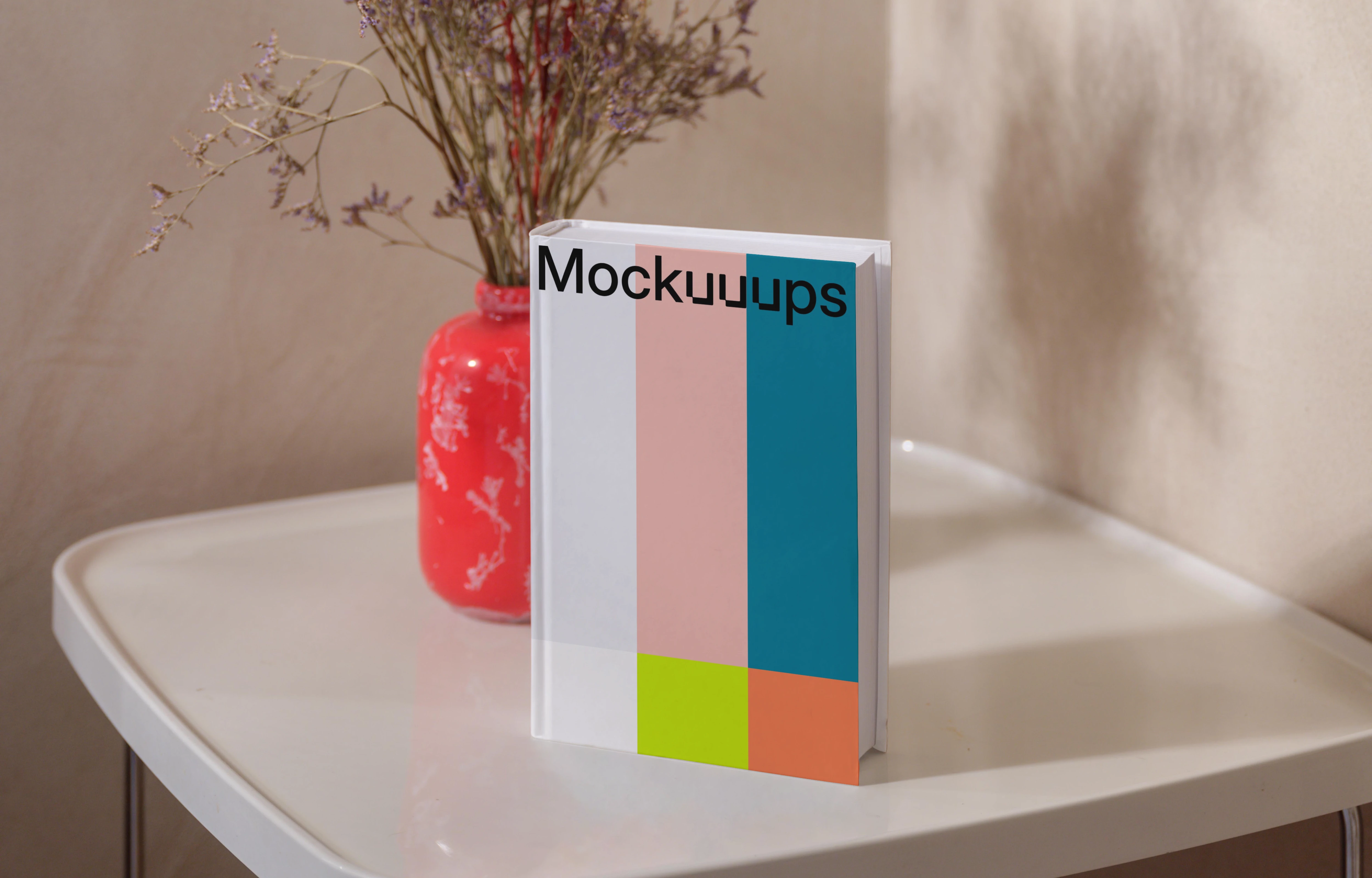 B-format book mockup on a white table with a red vase