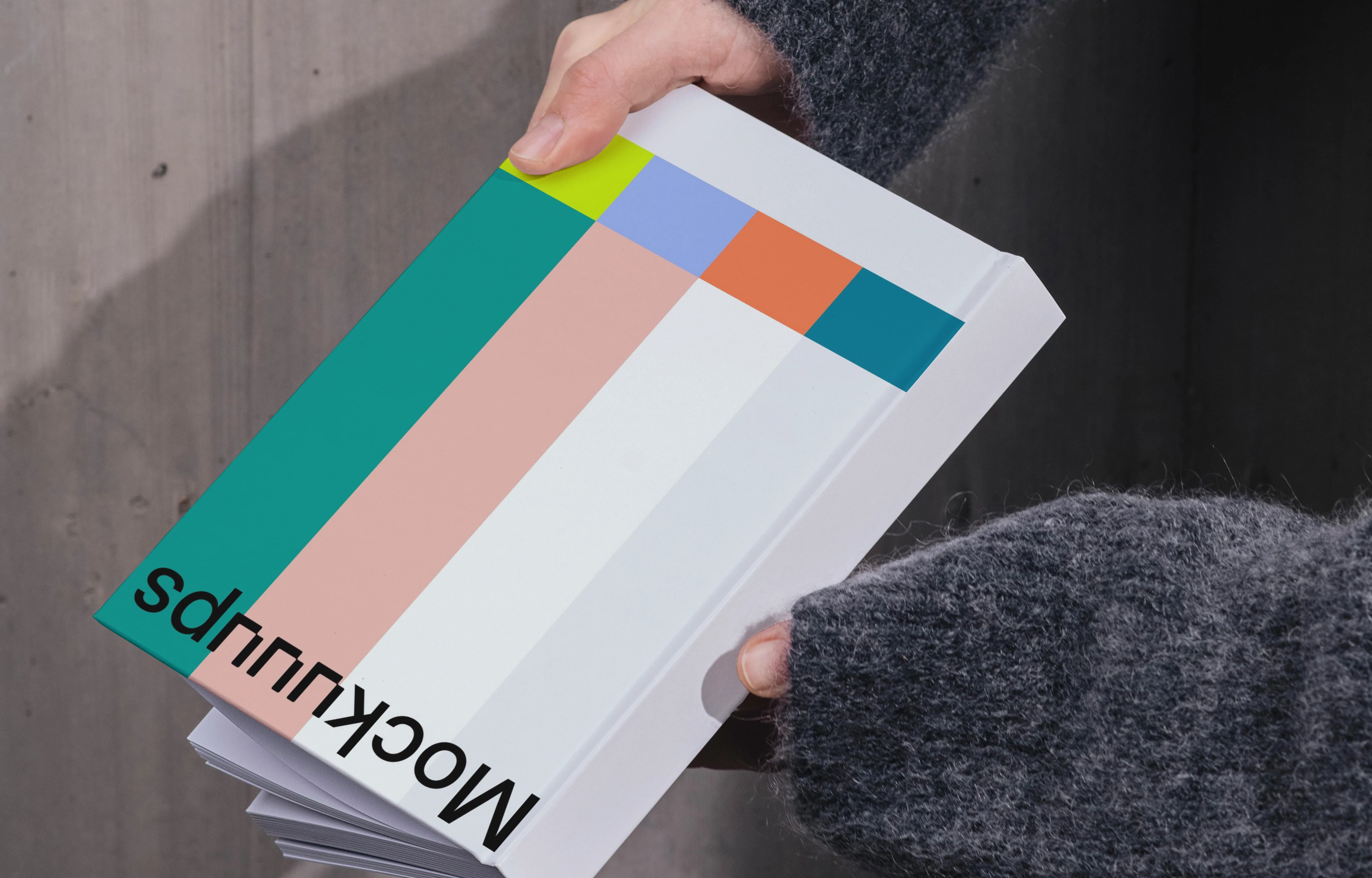 Book mockup held against a concrete wall