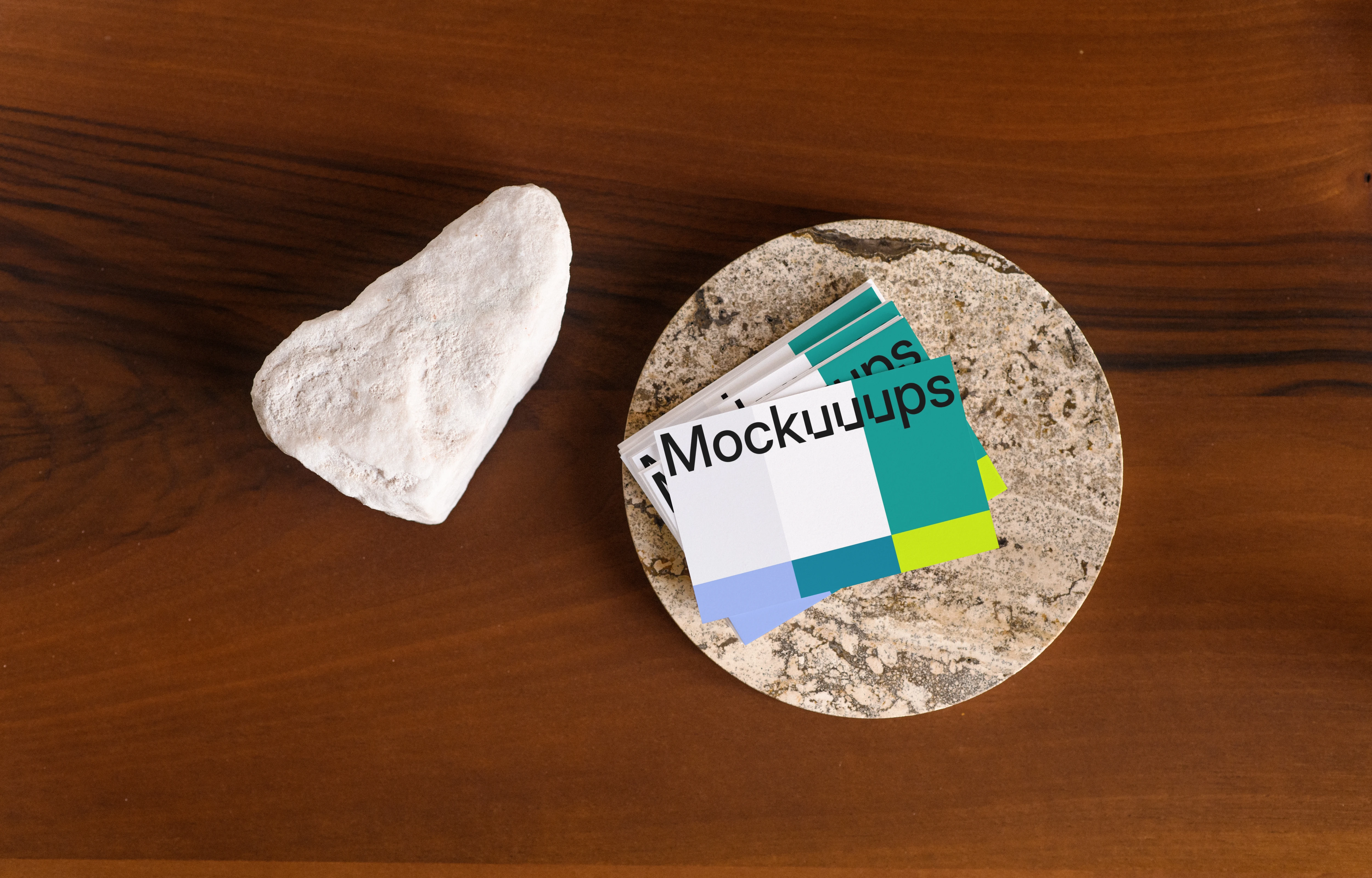 Business card mockup on a stone coaster with a wooden table