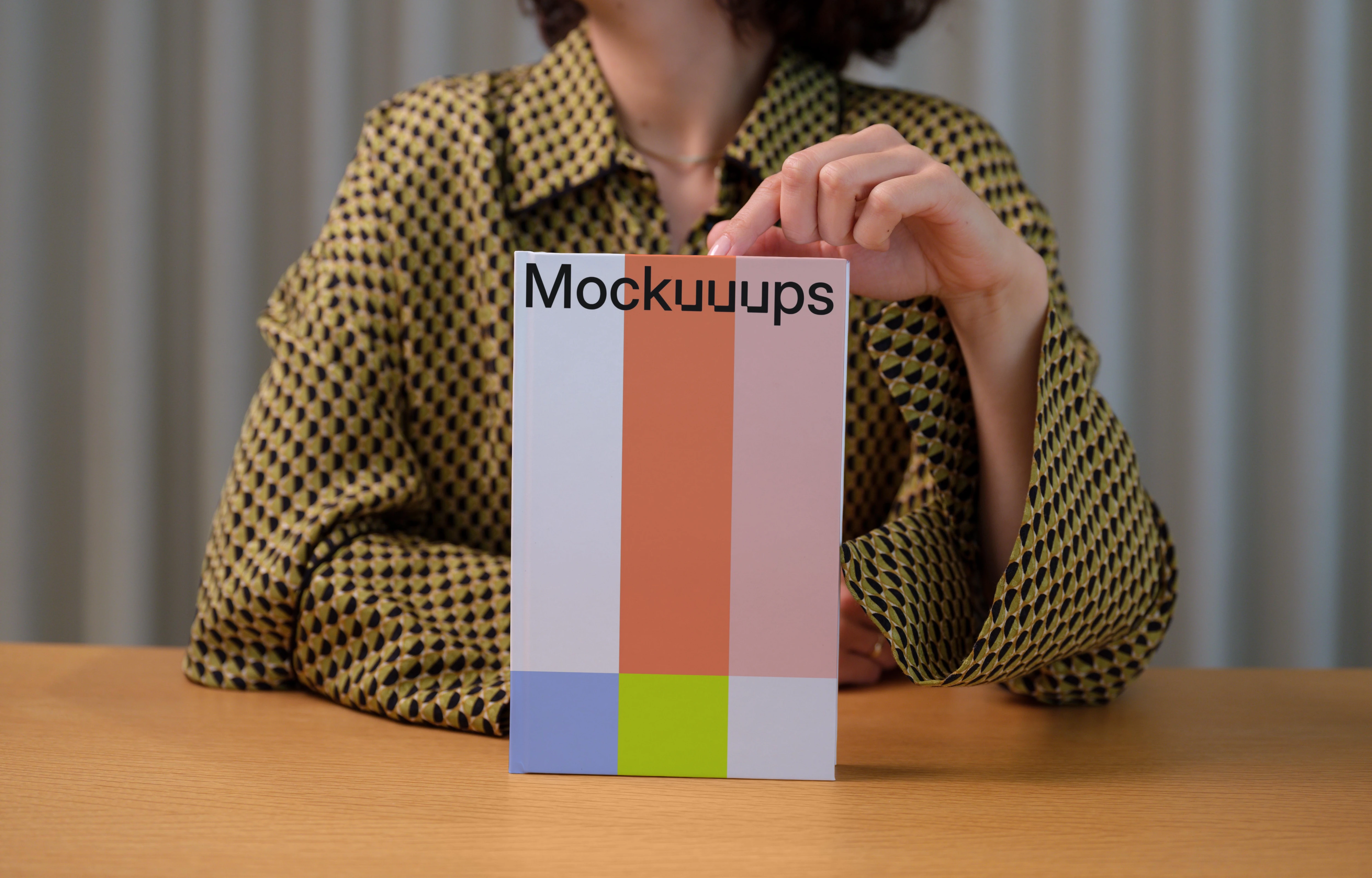 C-format book mockup held by person on wooden table
