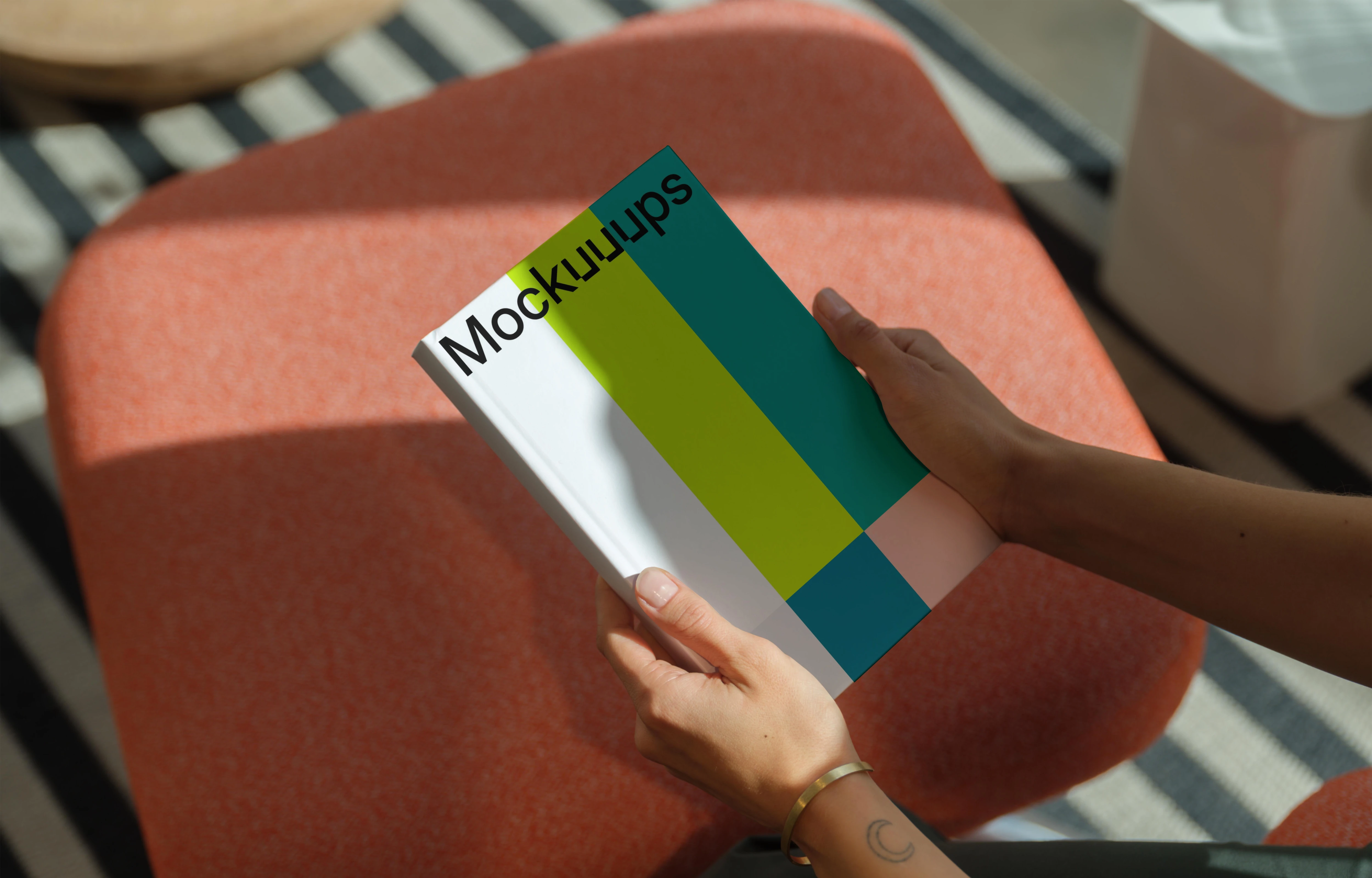 C-format book mockup in hands on a modern stool