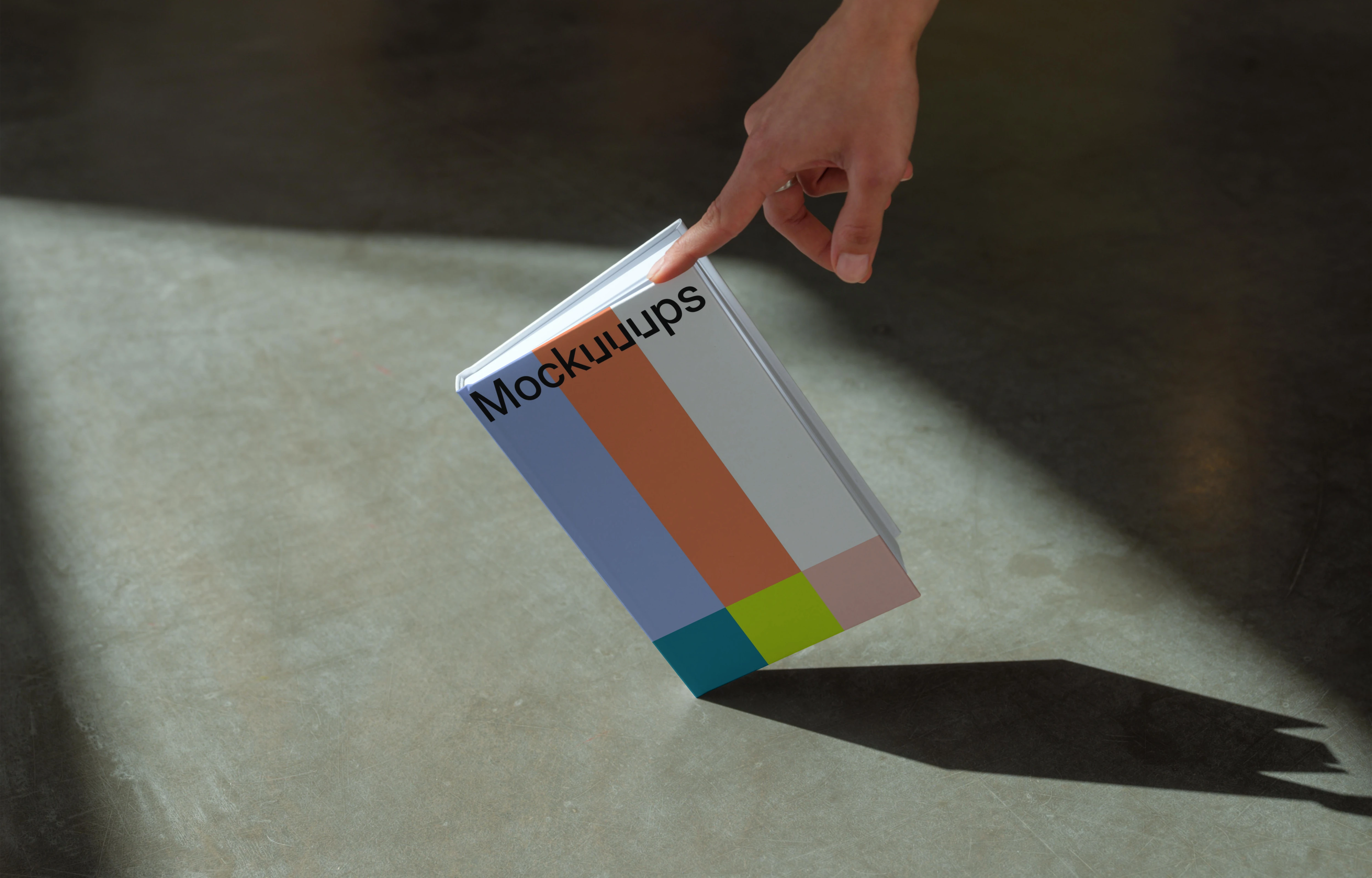 C-format book mockup with hand on concrete floor