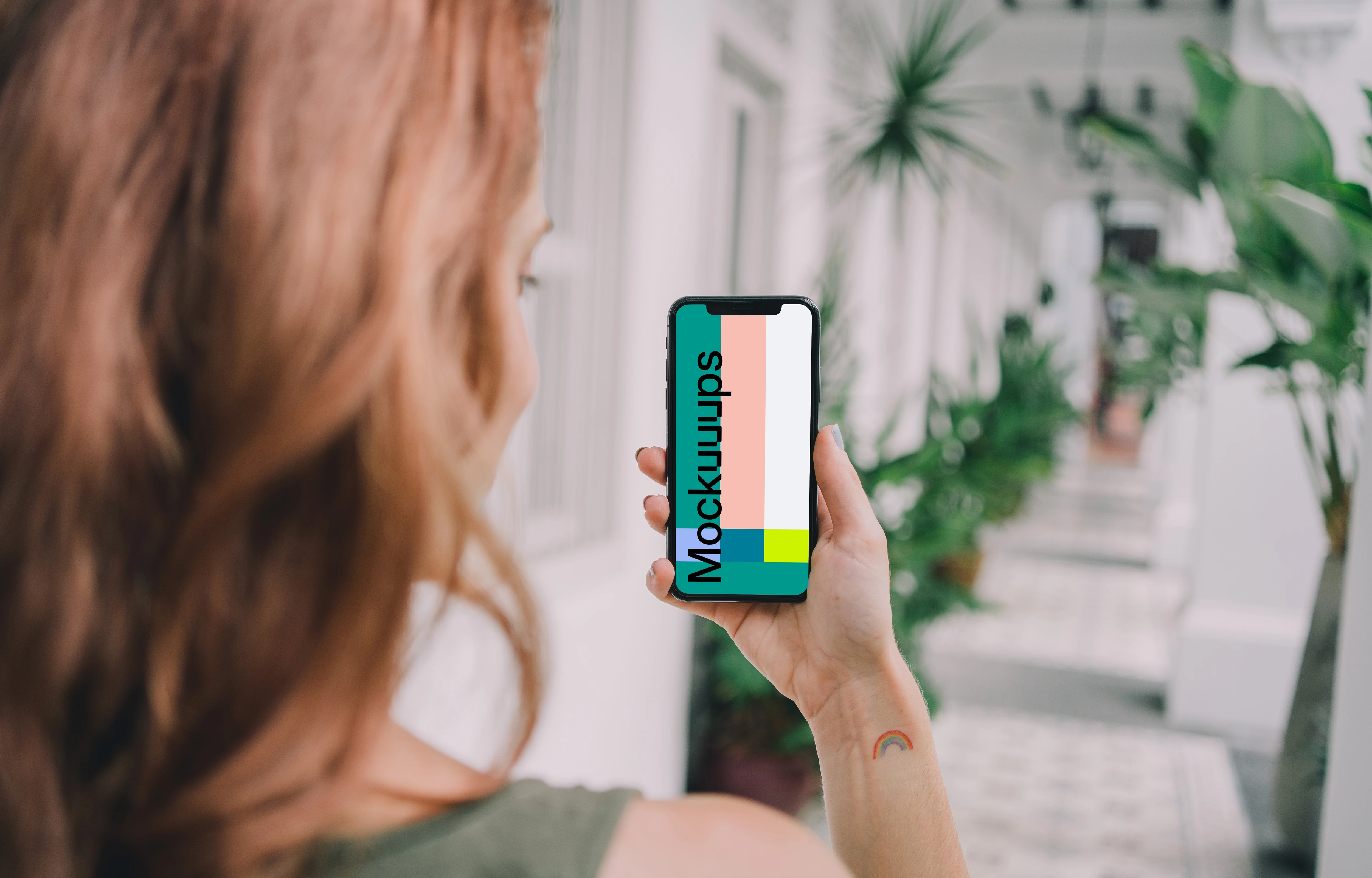 iPhone mockup held by user in a plant-filled corridor
