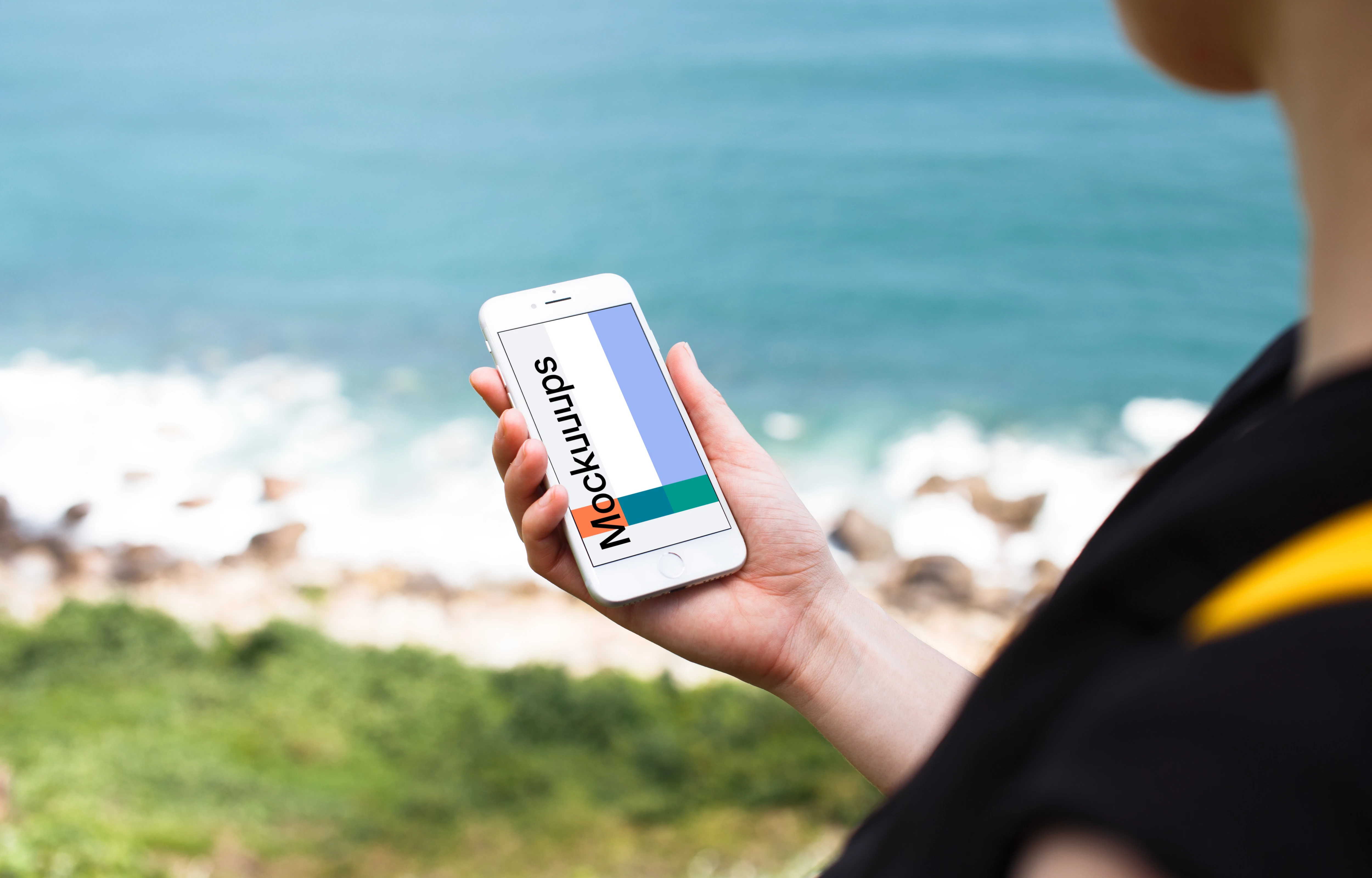 Holding iPhone 7 mockup next to the ocean