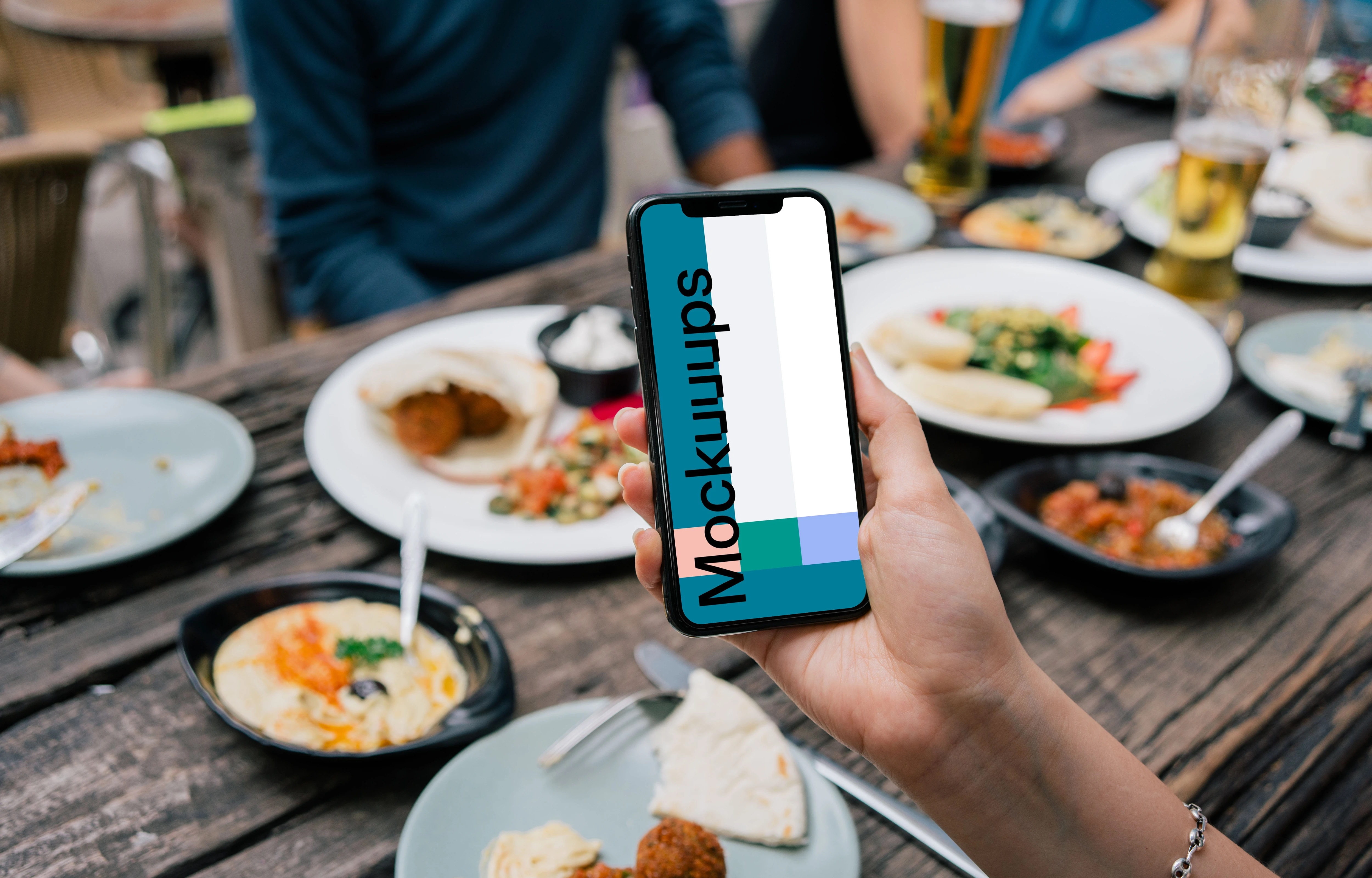 iPhone mockup in a user’s hand at dinner table
