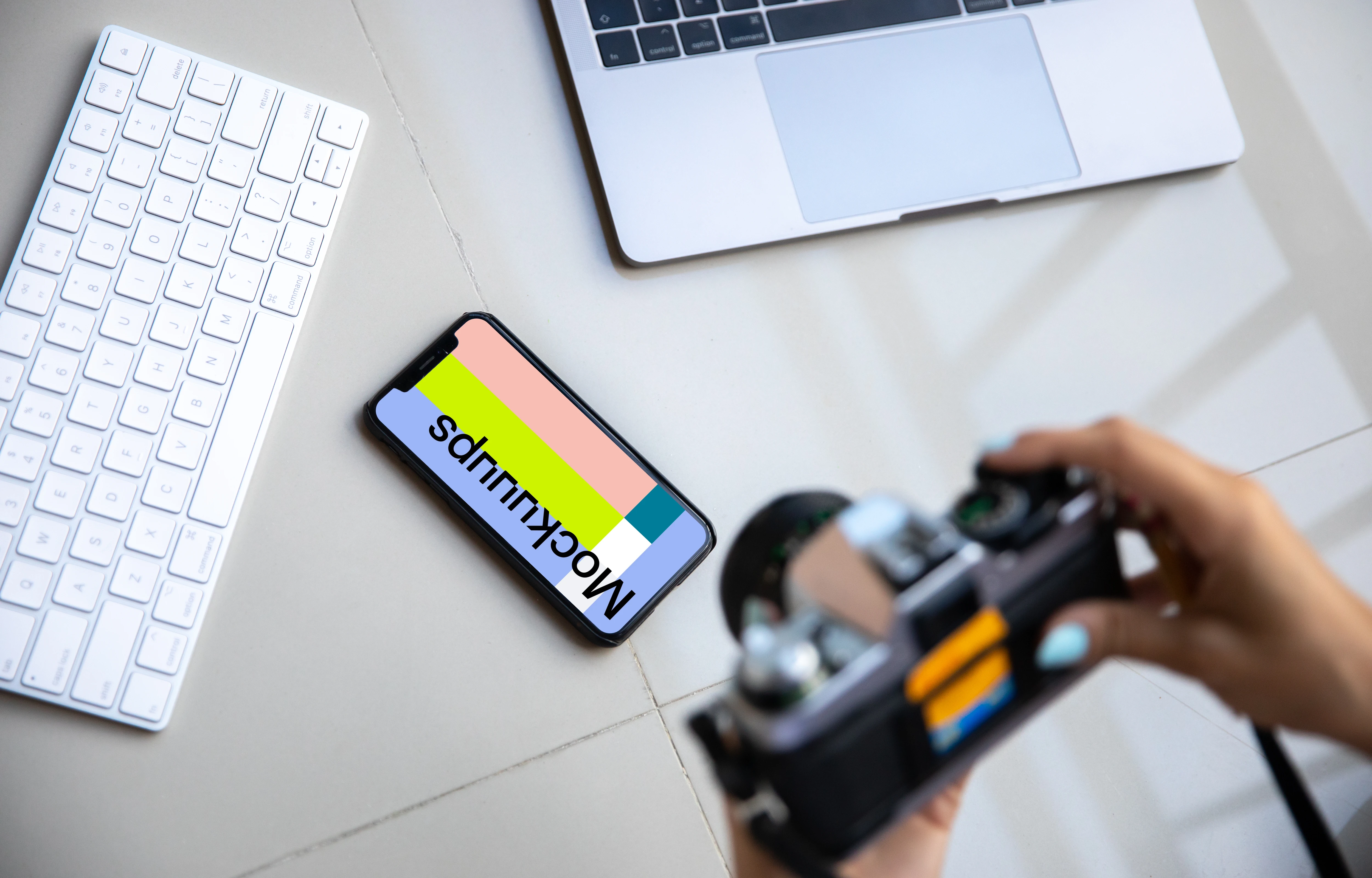 iPhone mockup on a table with a Macbook at the side