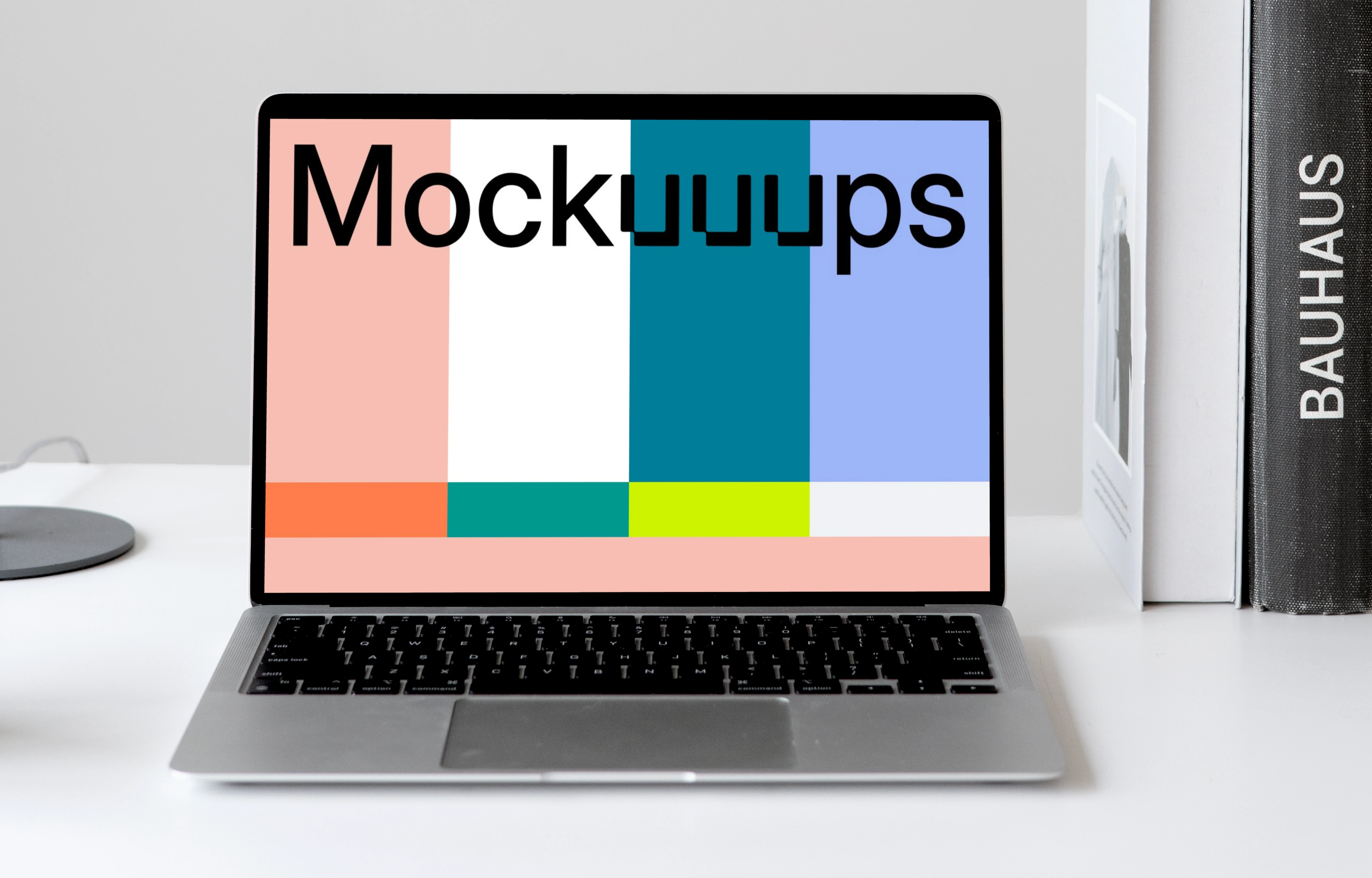 MacBook mockup on a white table with books stacked vertically at the side