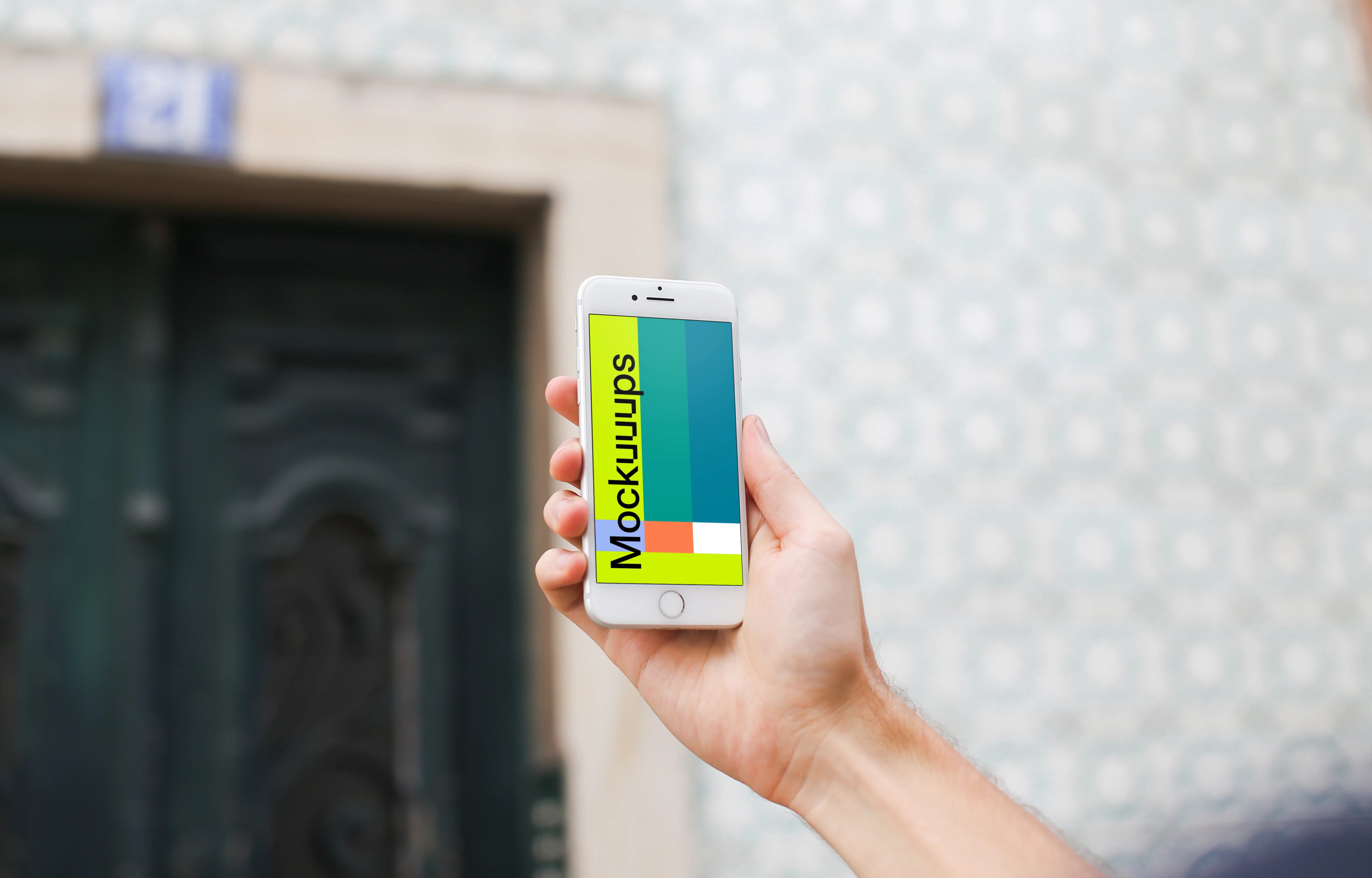 Man holding iPhone 7 mockup in front of the wall