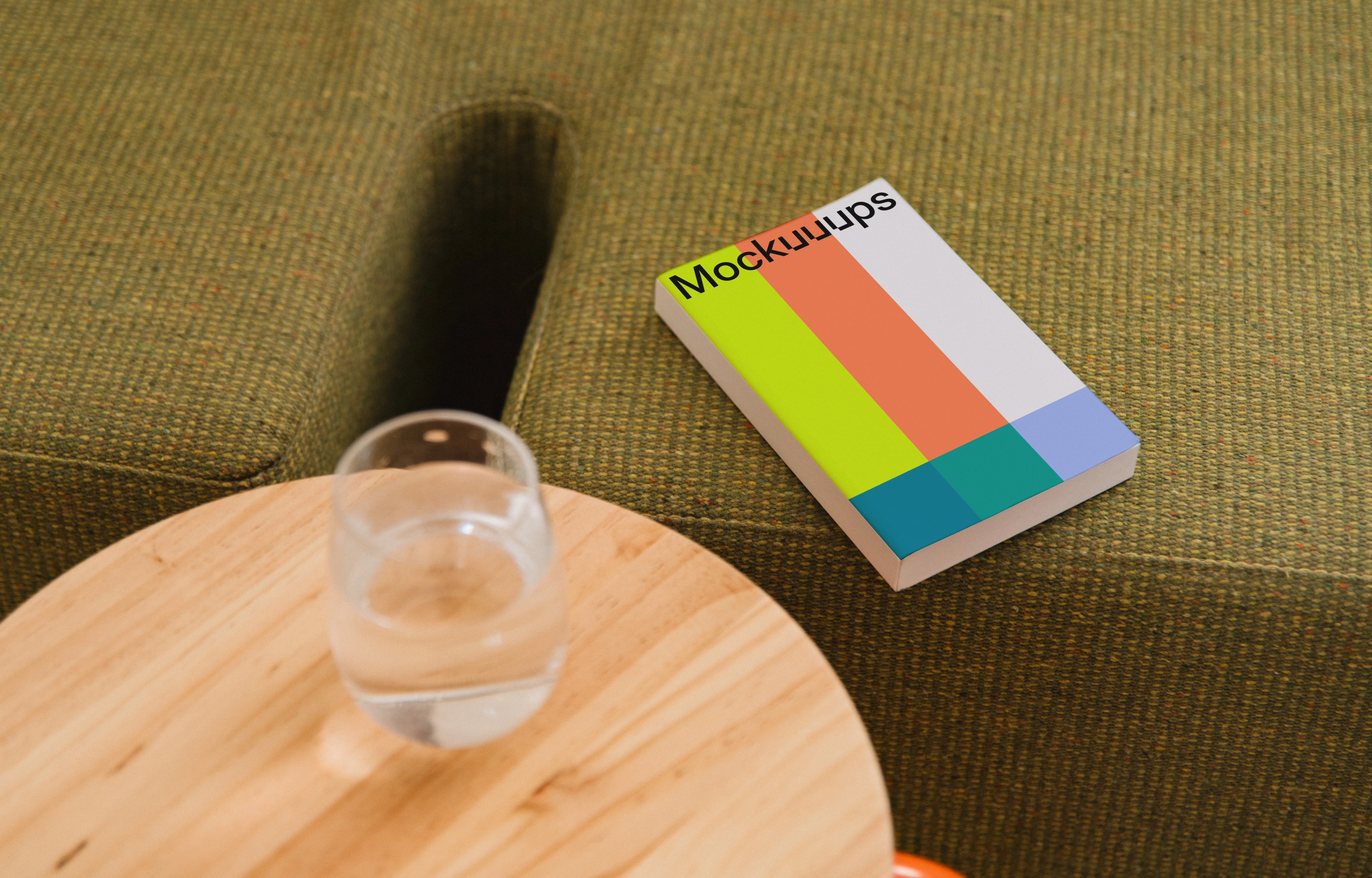 Paperback book mockup on a cozy green sofa