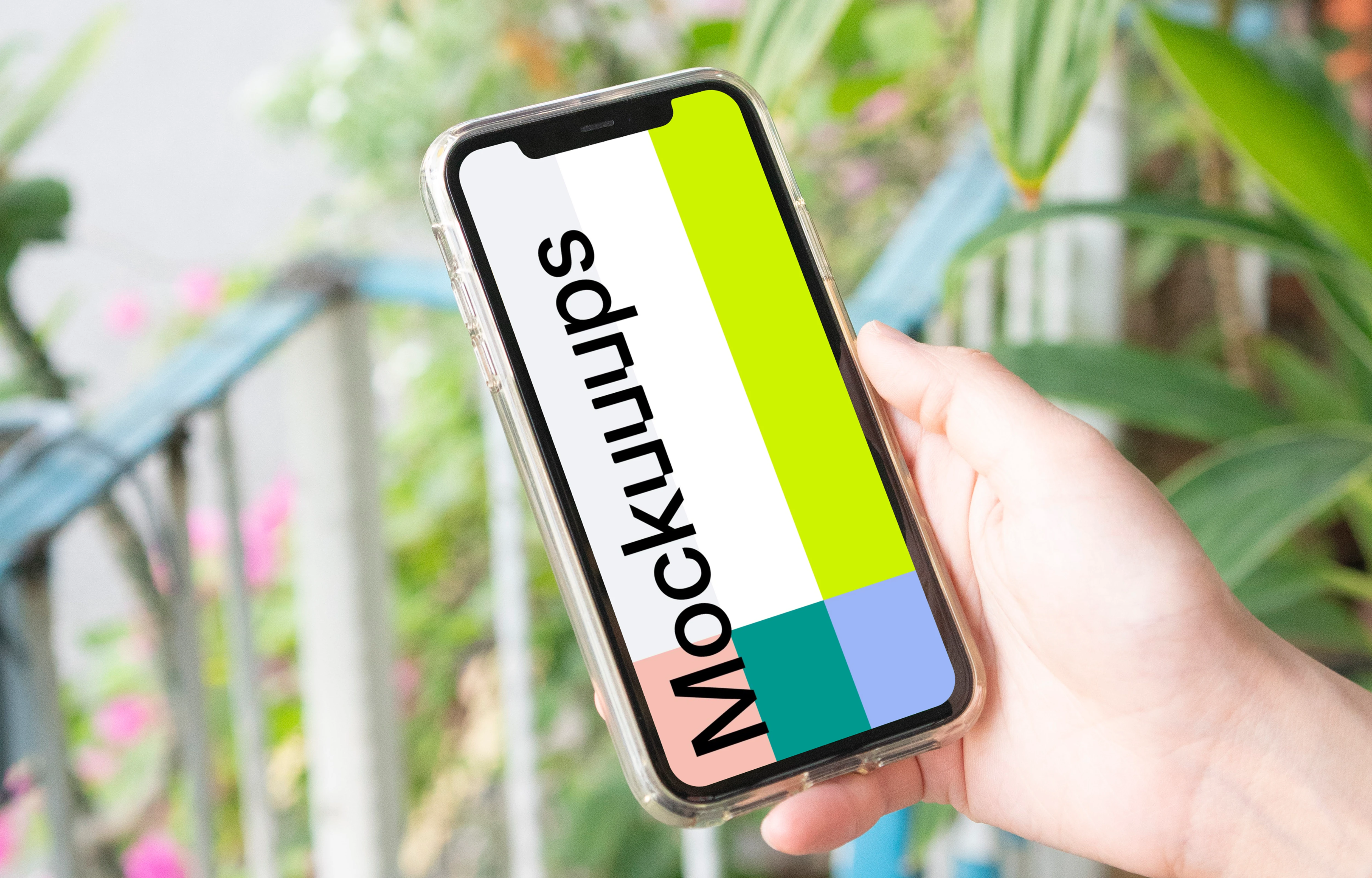 User holding up iPhone in a garden mockup