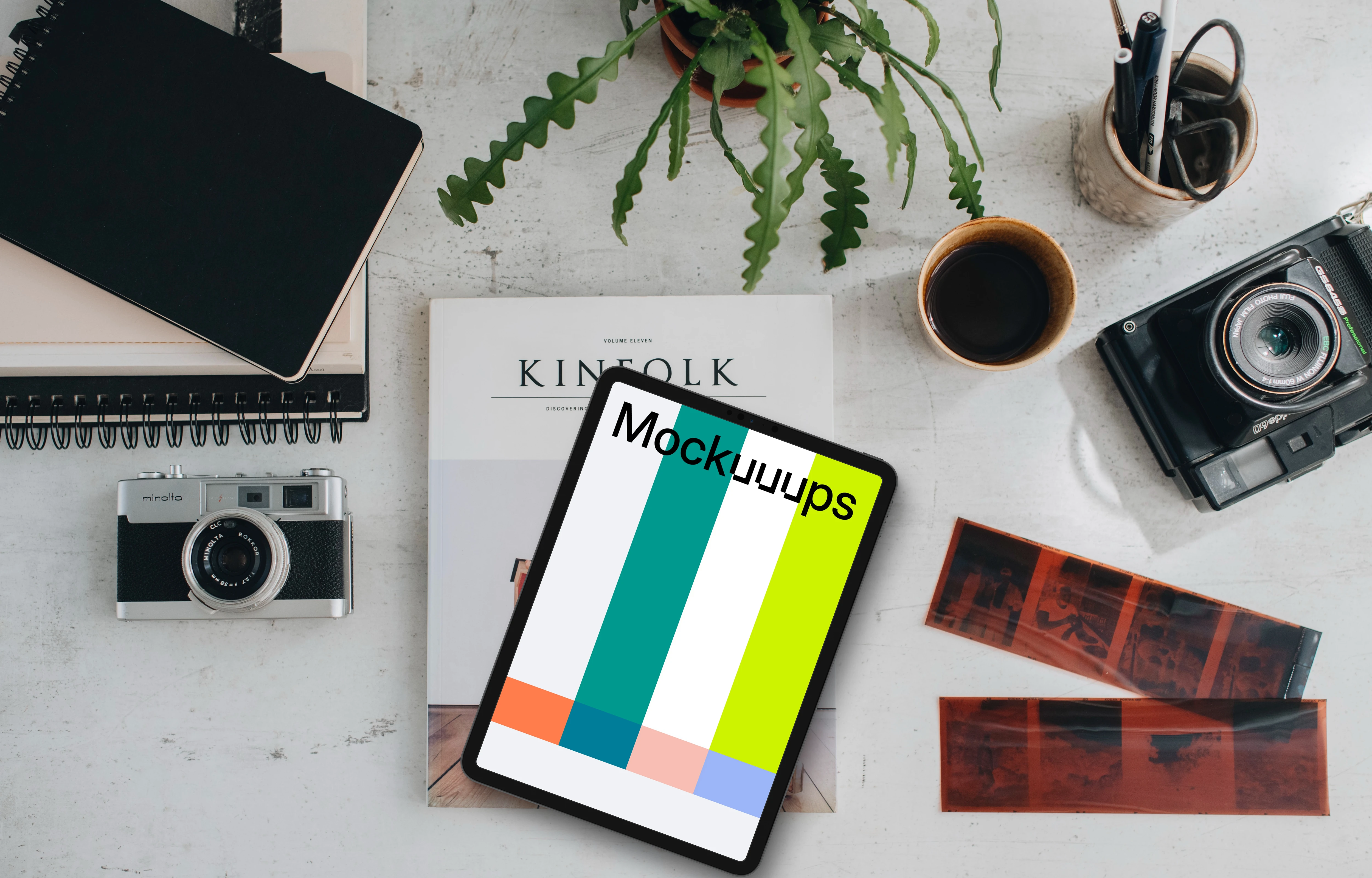 Top view of tablet mockup surrounded by analog cameras and negatives