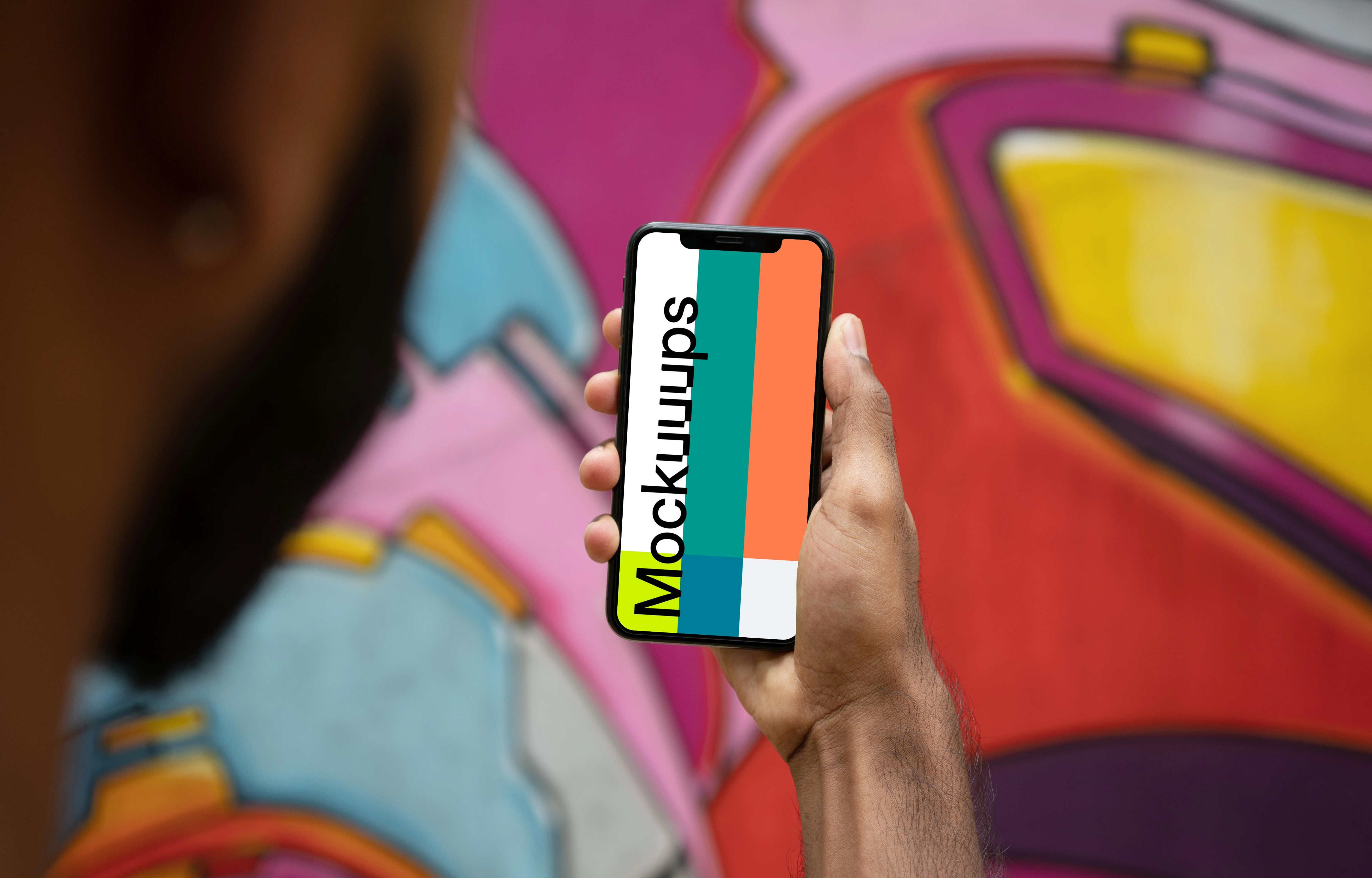 User holding iPhone in front of graffiti mockup