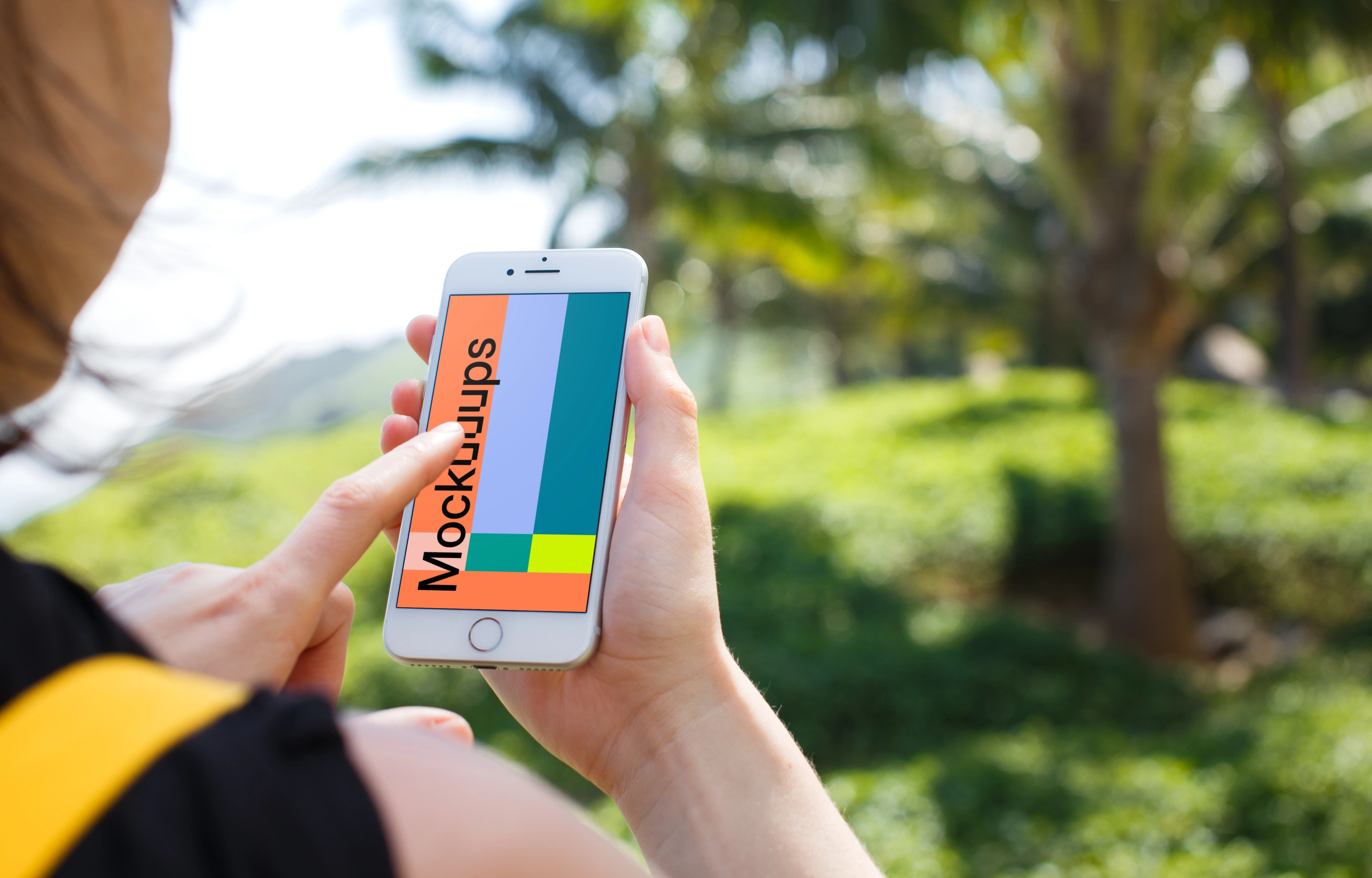 Woman holding iPhone 7 mockup in front of the palm tree