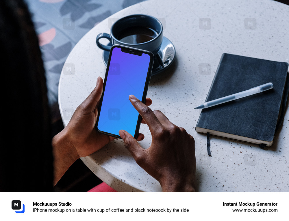 iPhone mockup on a table with cup of coffee and black notebook by the side