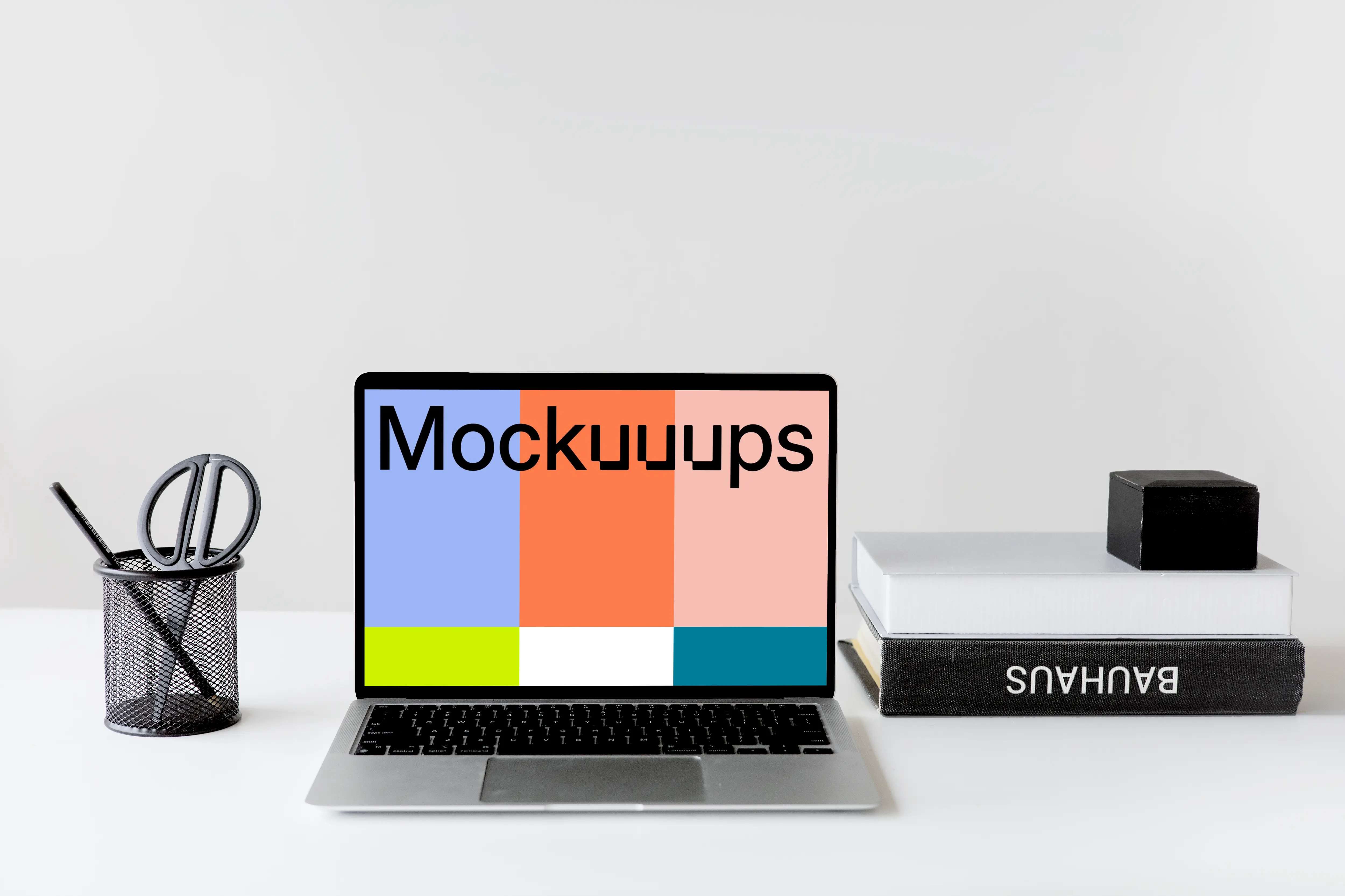 Black MacBook mockup on a white table with black textbooks at the side