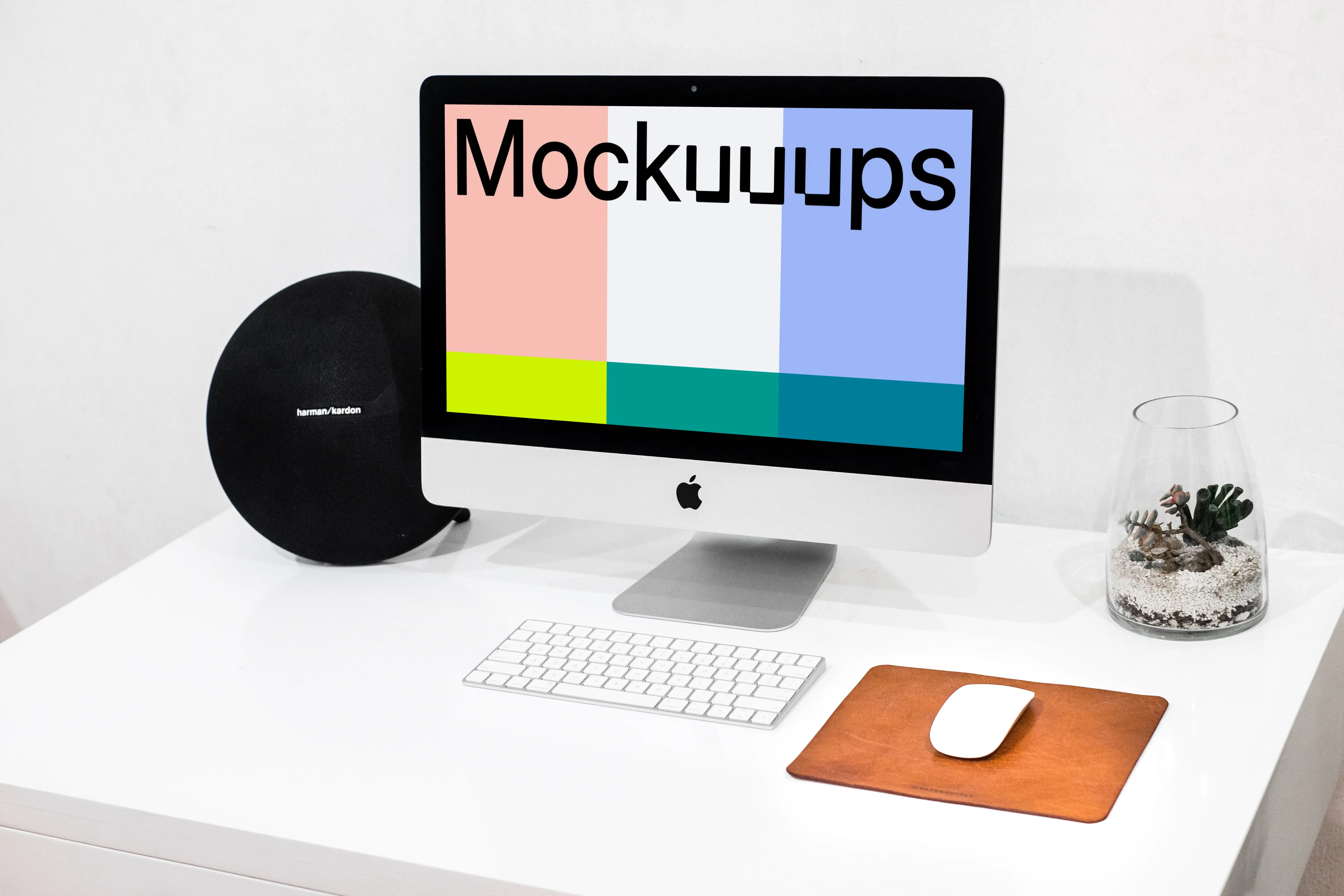 iMac mockup on a tidy work table beside a water vase