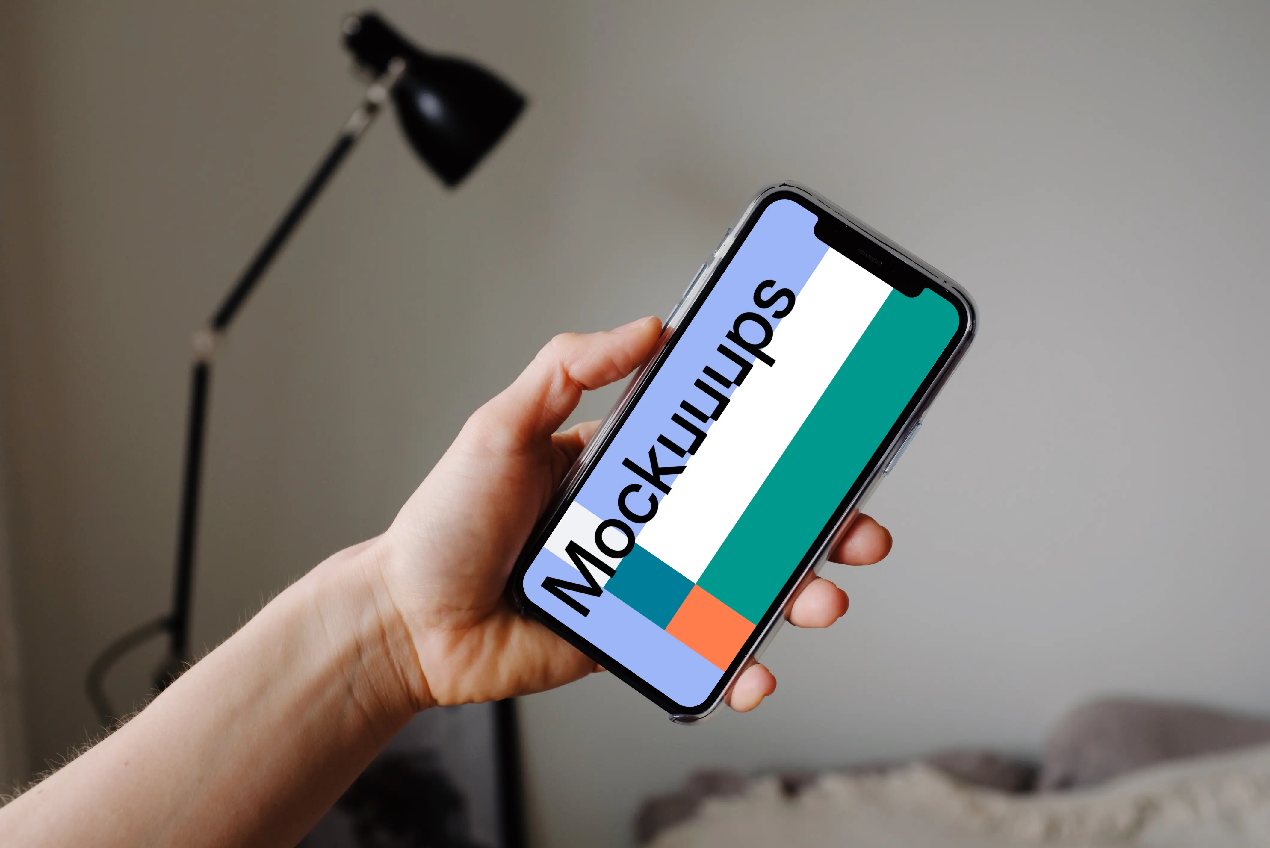 iPhone 12 Pro mockup held by user with a reading lamp in the background