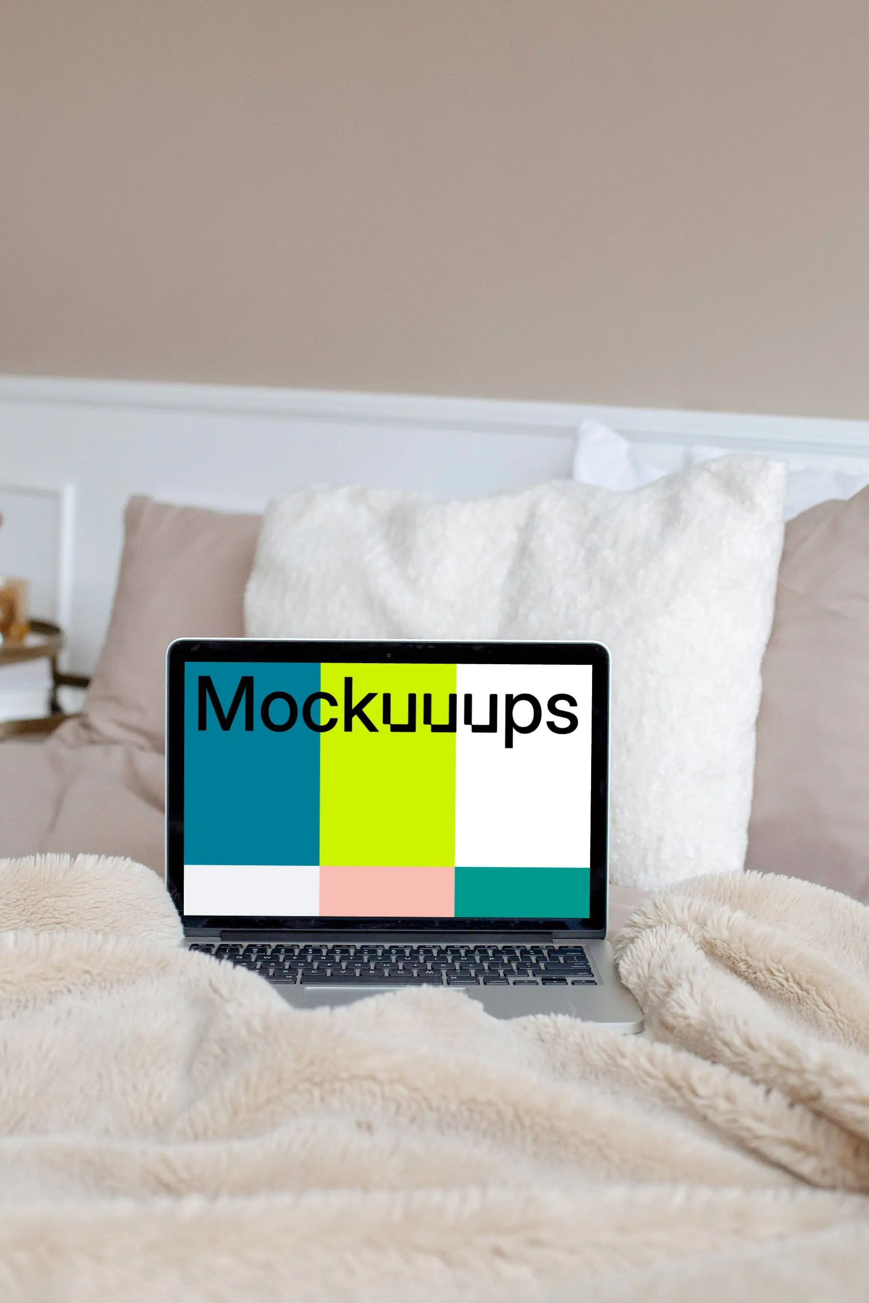 MacBook mockup on a cream-colored bed with white pillows in the background