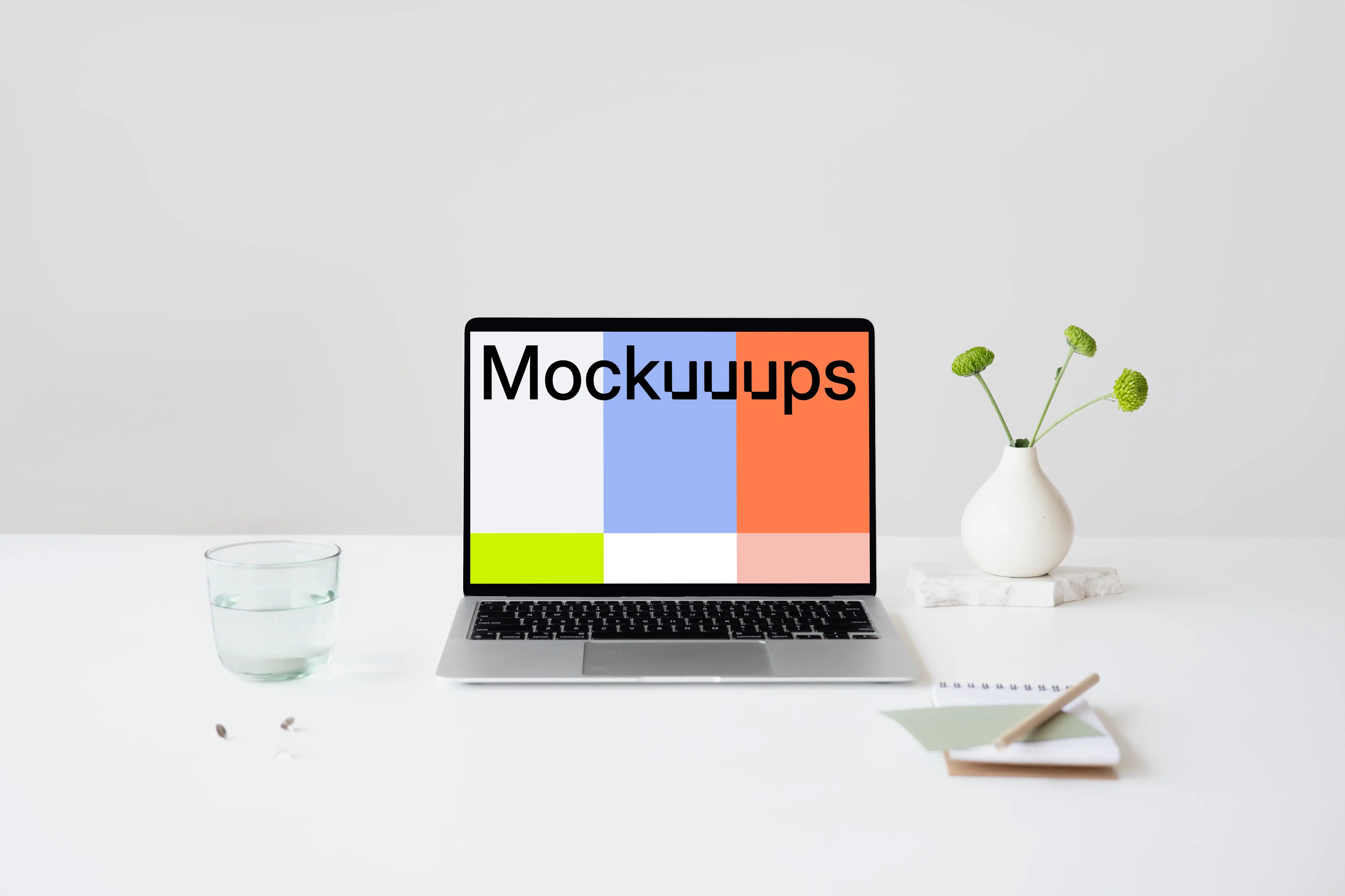 MacBook mockup on a table with glass of water at the side