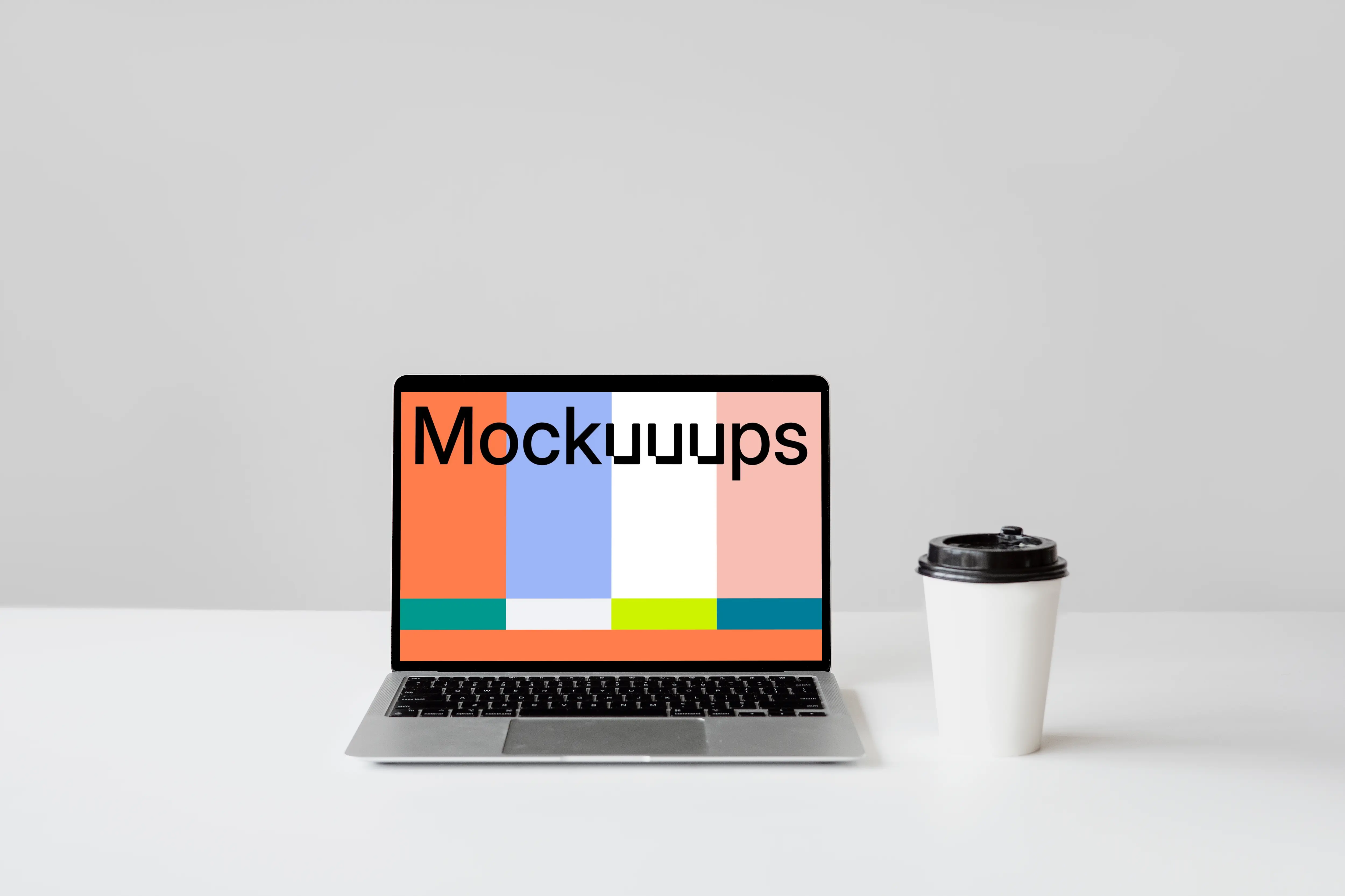 MacBook mockup on a white table with a disposable coffee cup at the side