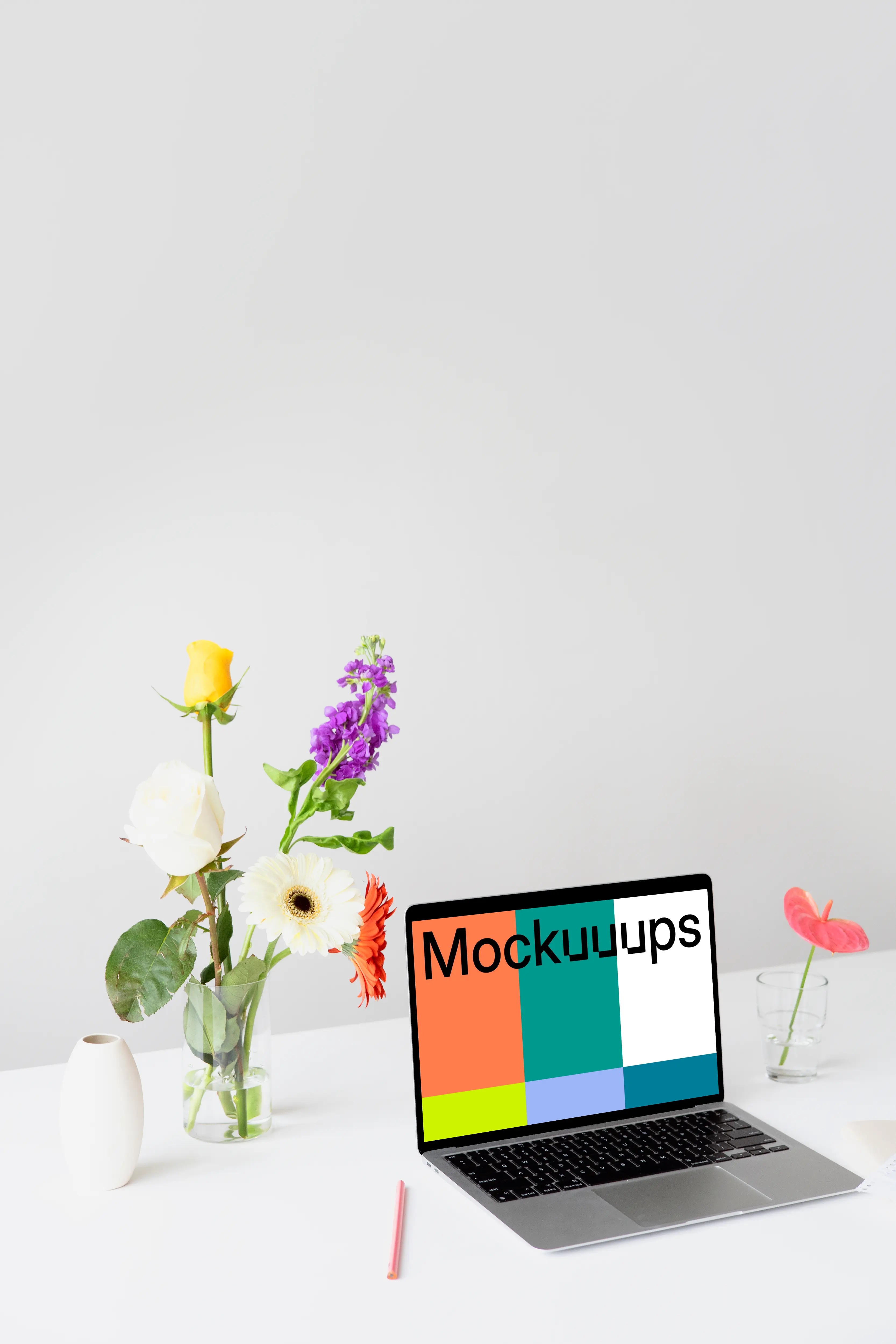 MacBook mockup on a white table with beautiful flowers in a transparent vase