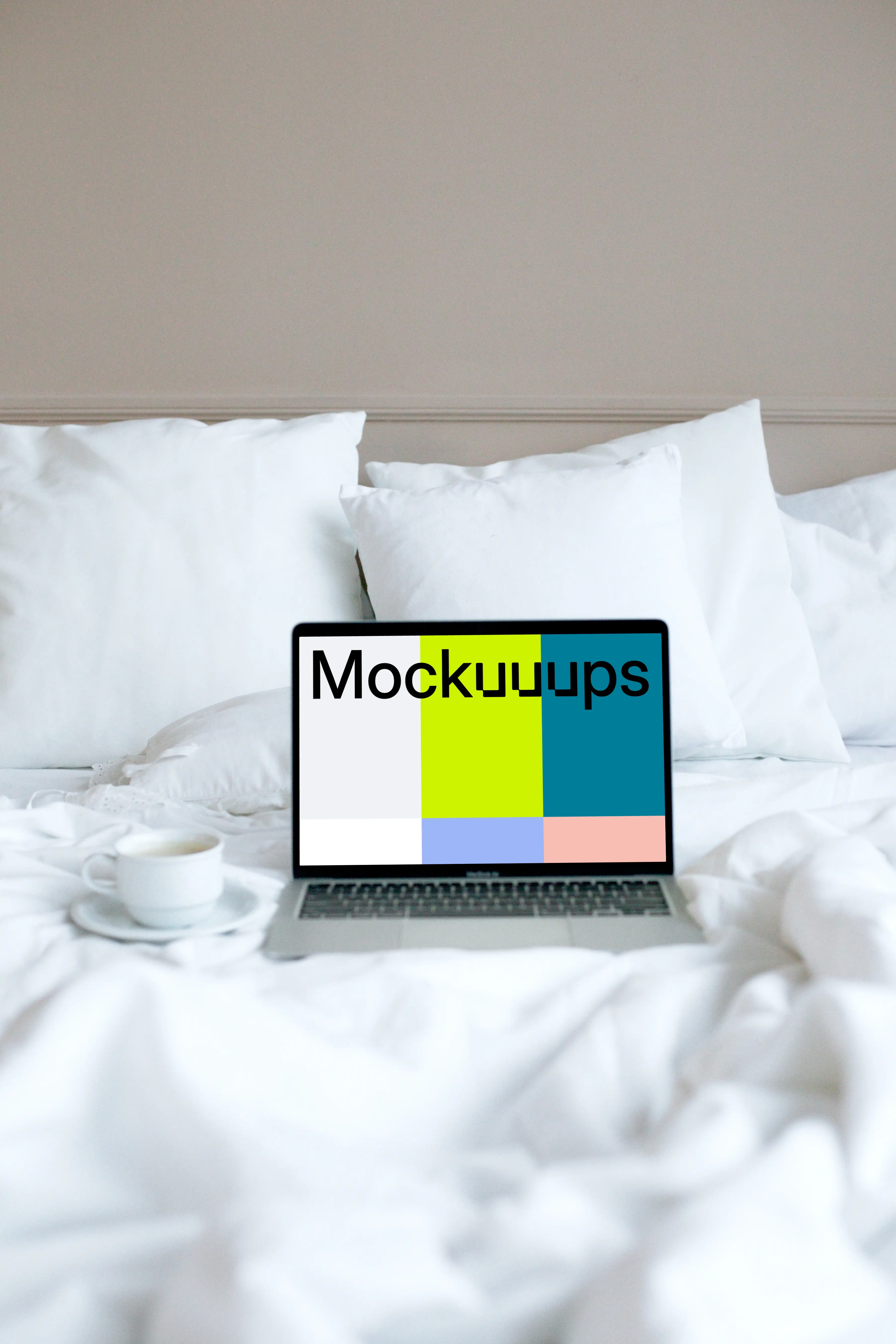 MacBook mockup placed on a white bed with a cup of coffee at the side