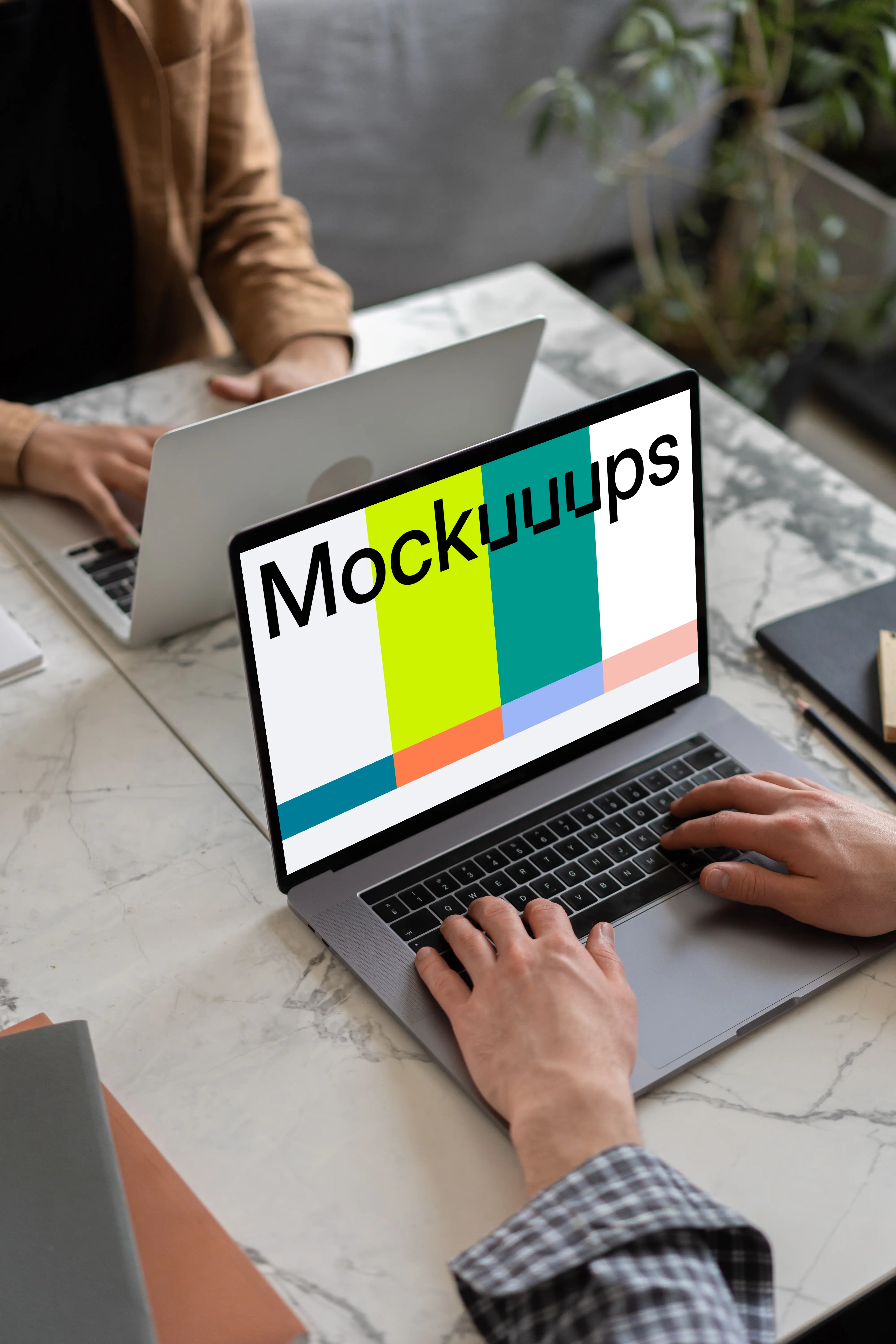 Notebook mockup on a table opposite another MacBook Pro