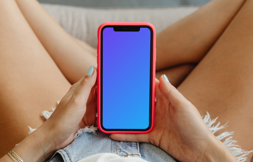 Primer plano iPhone Mockup en manos de una usuaria con pantalones cortos vaqueros