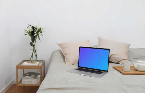 MacBook mockup em uma cama com um jogo de chá ao lado