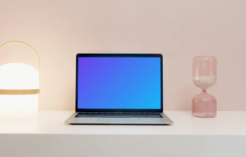 MacBook Pro mockup on a table beside an hourglass